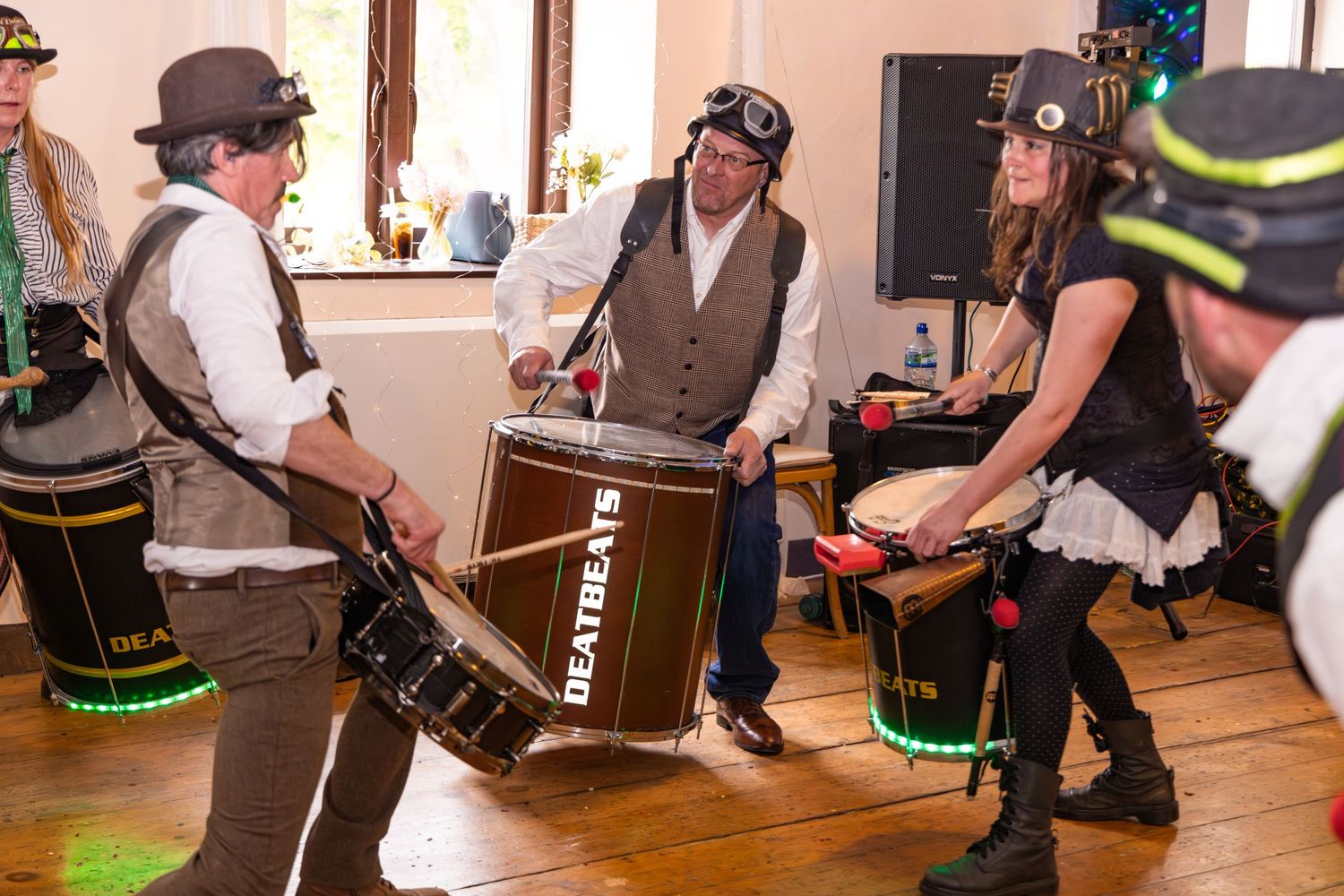Steampunk drummers performing with LED lit drums at lively event.