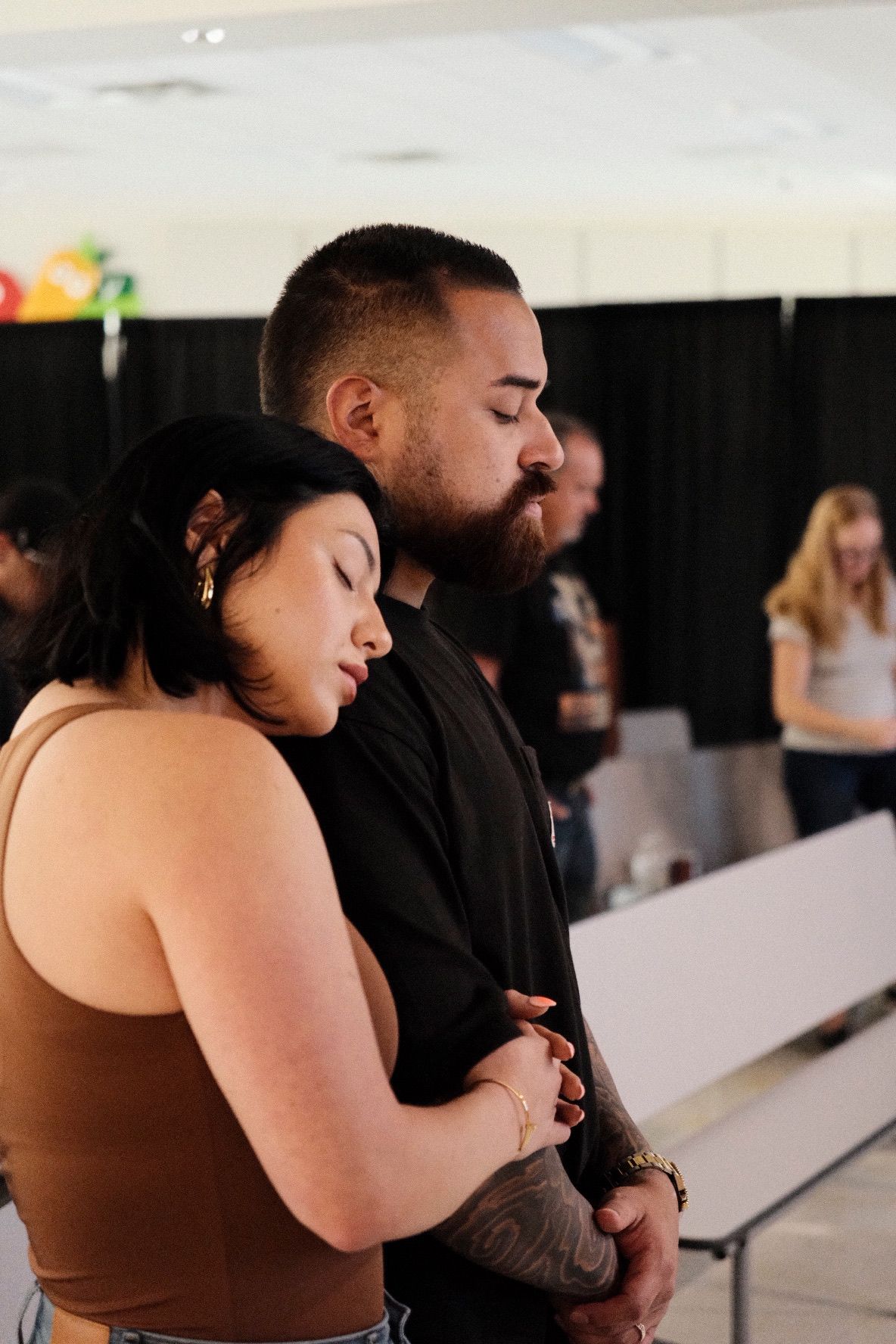 Young couple embracing with eyes closed in peaceful prayer at church service.