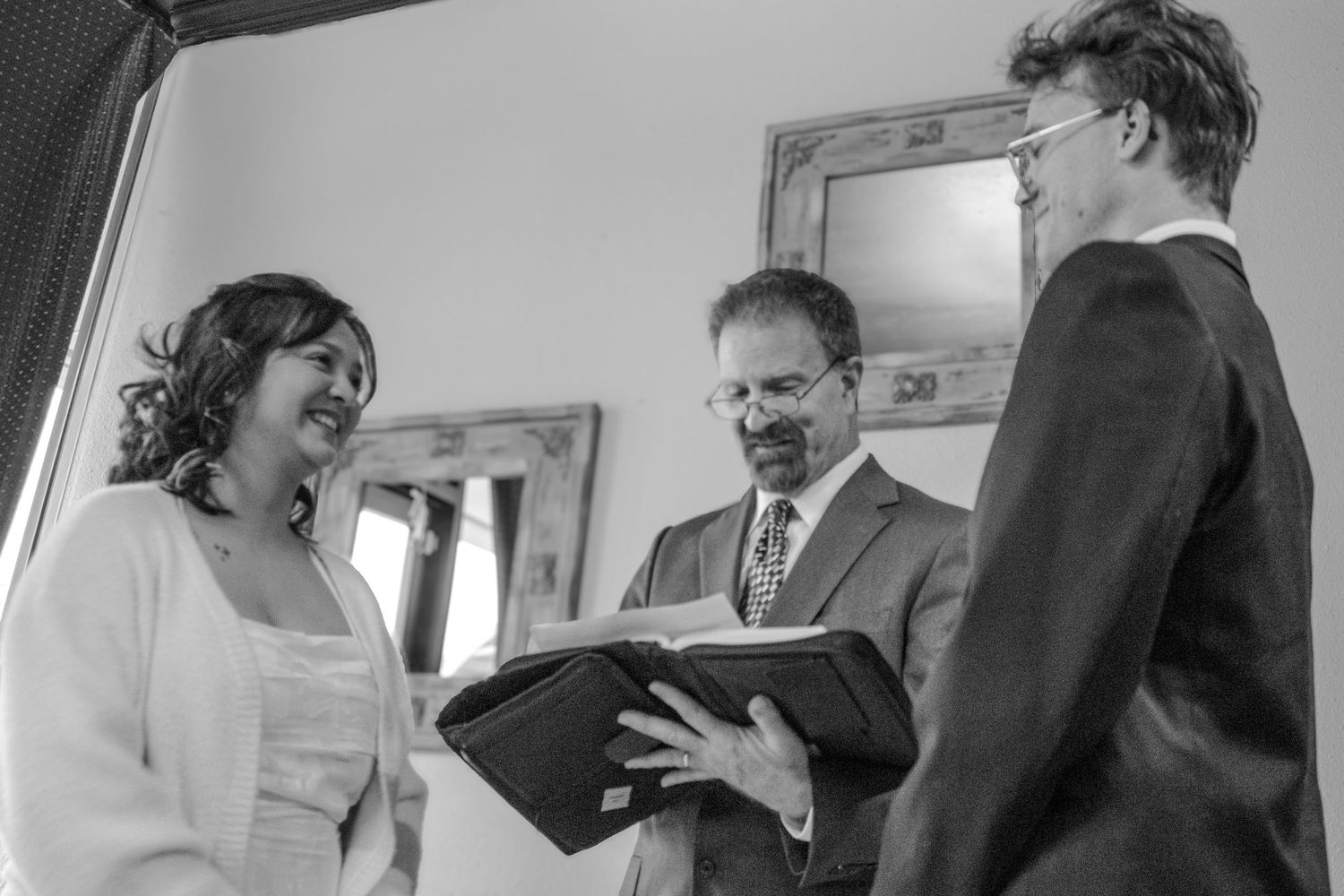 An officiant reads from a book during an intimate indoor wedding ceremony with the bride and groom.
