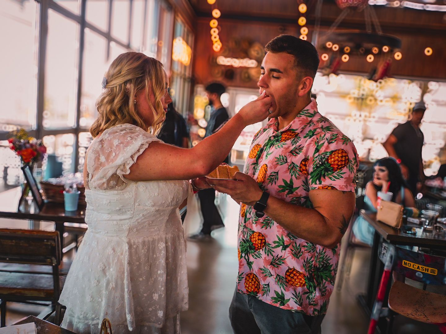 Couple sharing a playful moment at a lively indoor venue with festive string lights in background.