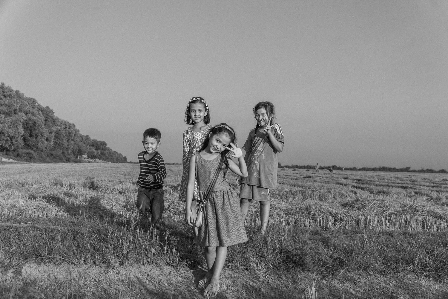 Photo de voyage en noir et blanc de quatre enfants cambodgiens dans un champ