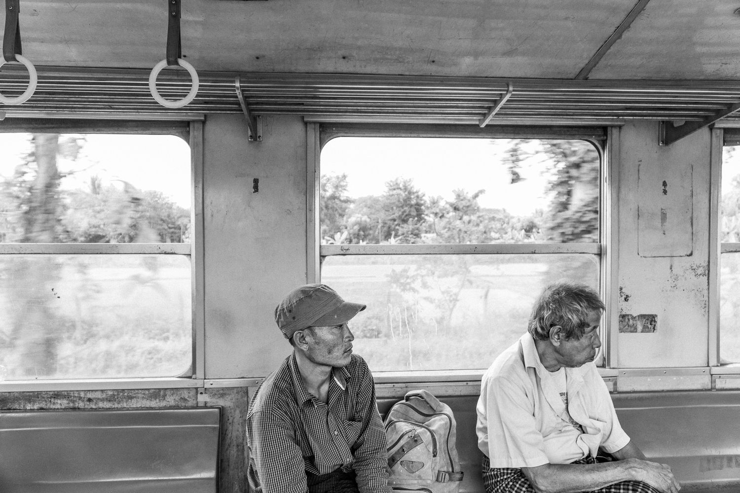 Photographie de voyage en noir et blanc de deux hommes birmans assis dans un train