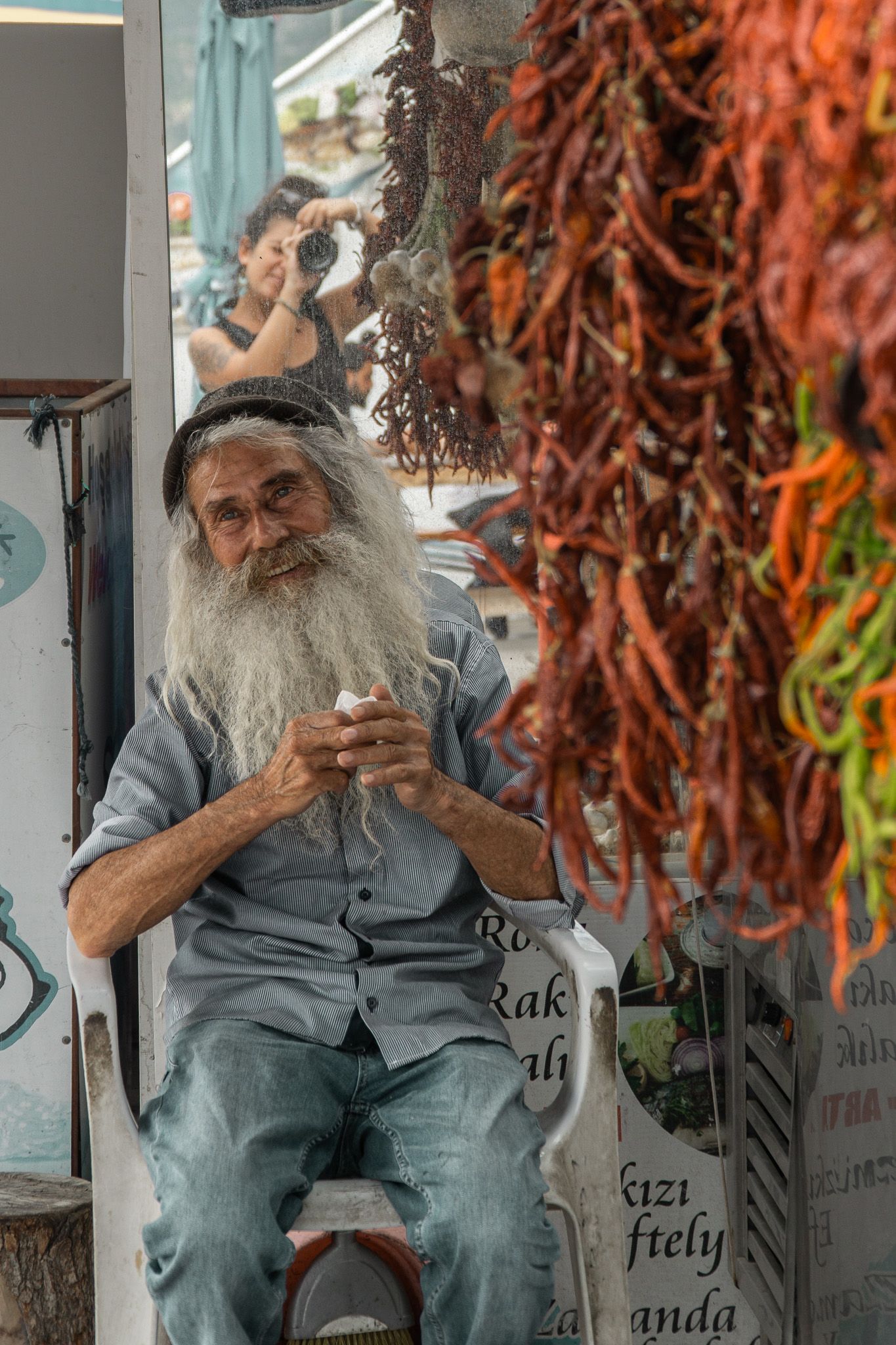 Portrait de voyage d'un vieil homme assis devant un étal de piments séchés