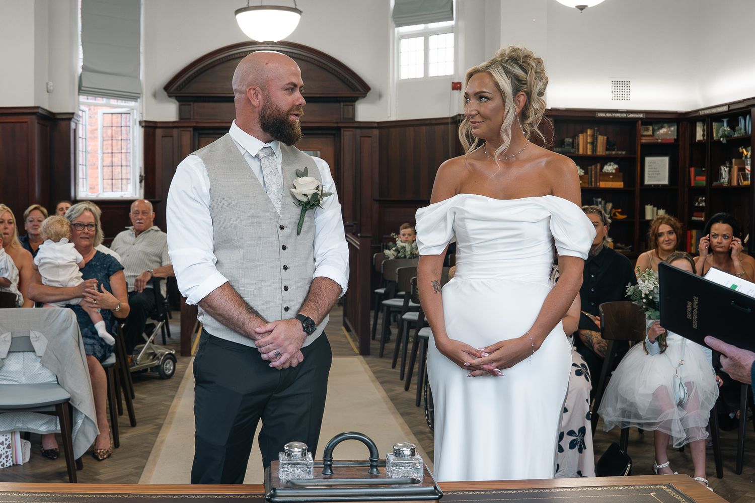 Bride and groom standing at altar during wedding ceremony with guests seated behind.