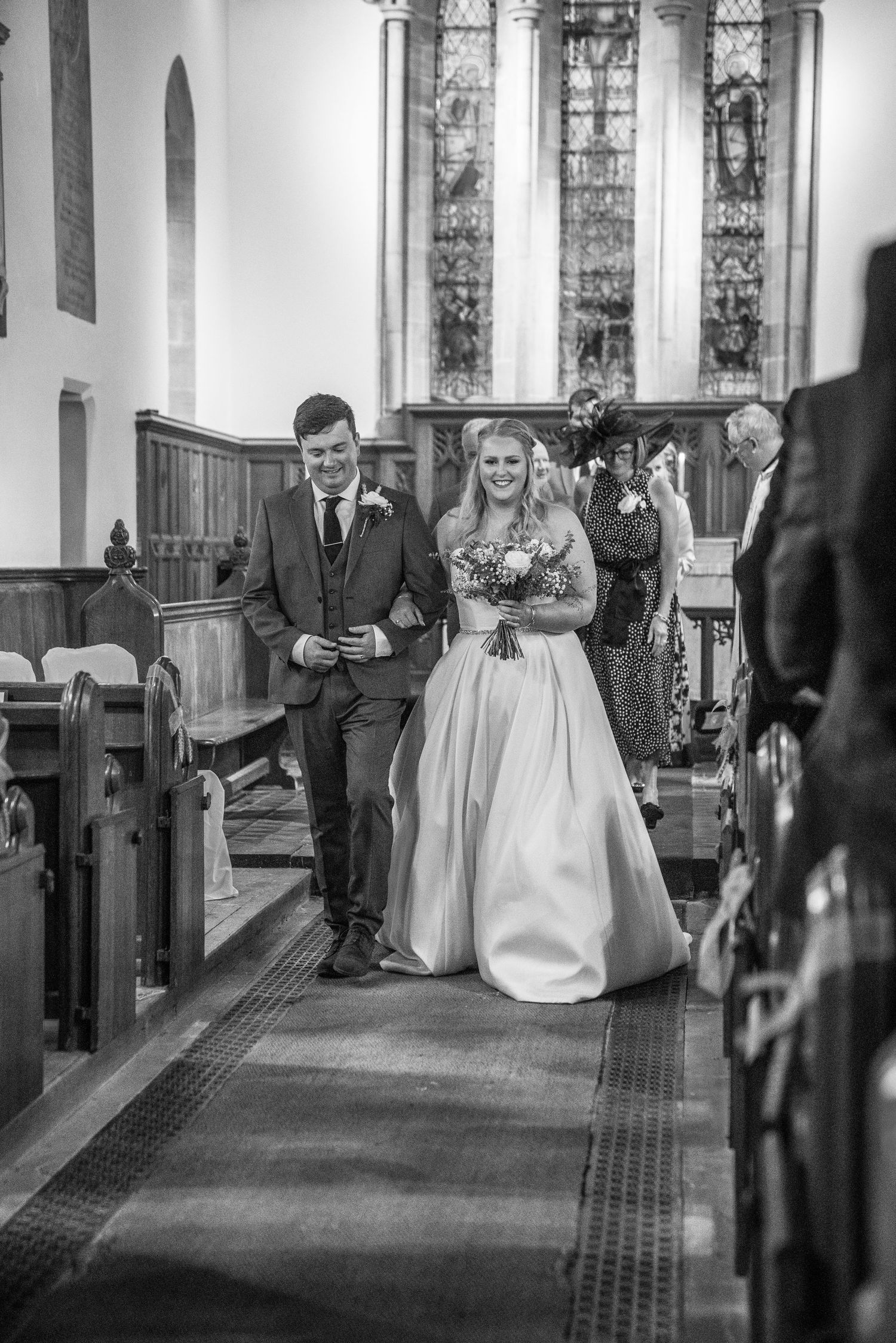 Bride and groom walking back down the aisle after their church wedding ceremony in black and white.