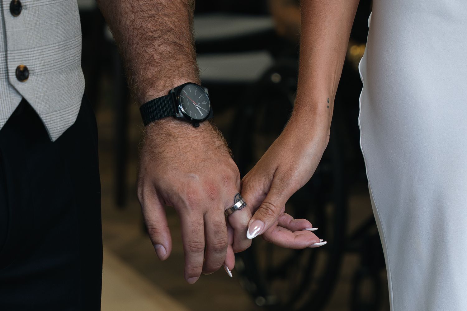 Close-up of newlyweds holding hands, bride wearing wedding ring after ceremony.