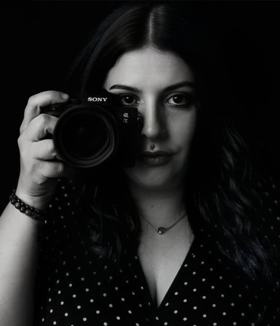 Female wedding photographer holds Sony camera in striking black and white portrait photo.