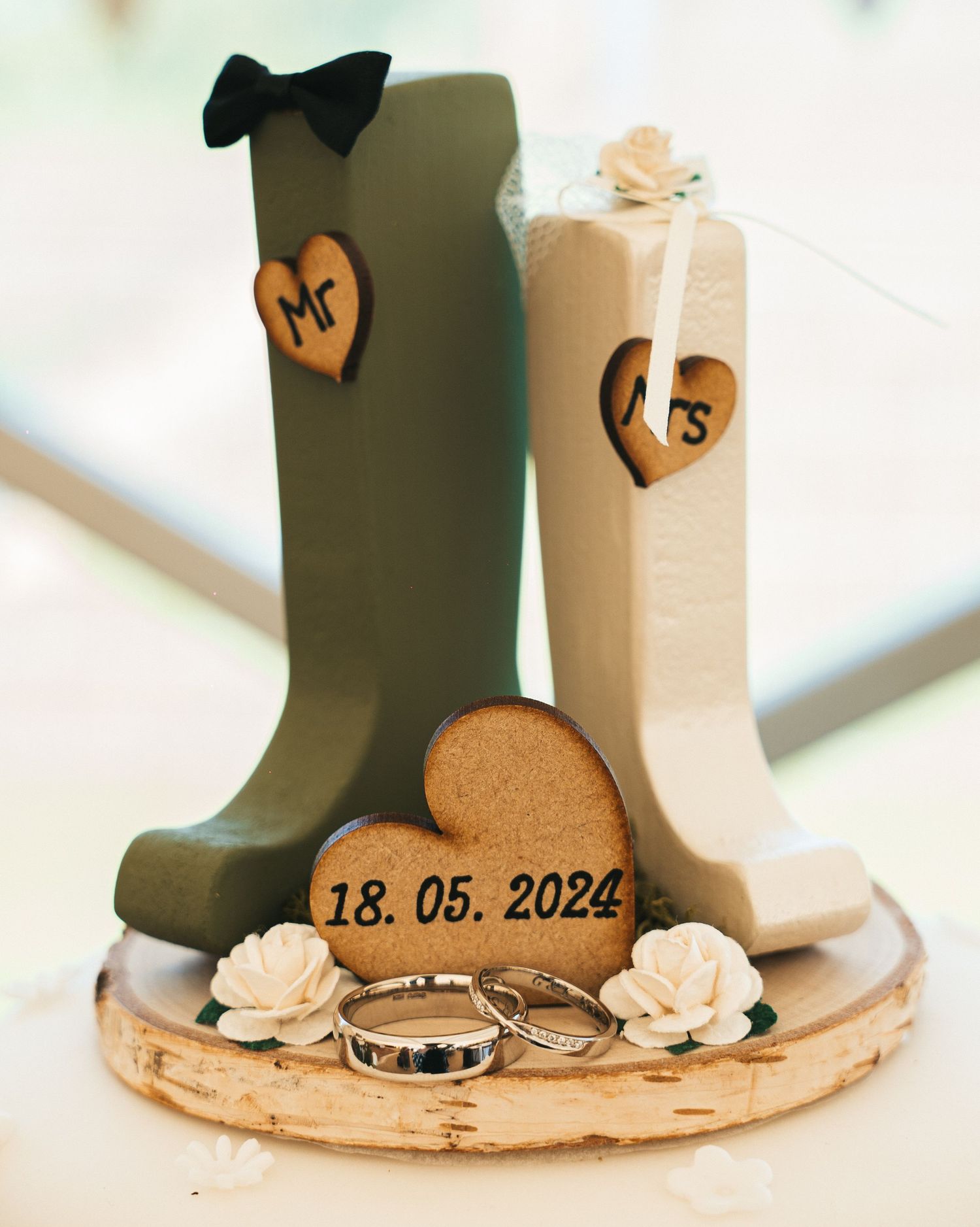 Wedding cake topper with Mr and Mrs figures and rings dated 18.05.2024 on wooden base.