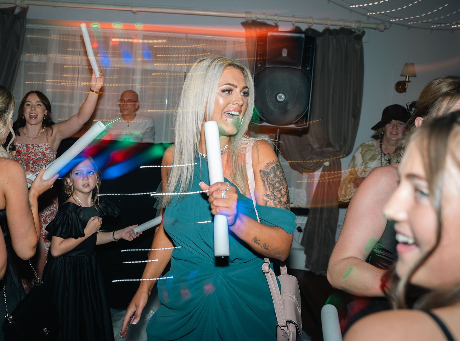Wedding guest dancing with glow sticks at a lively evening wedding reception party.