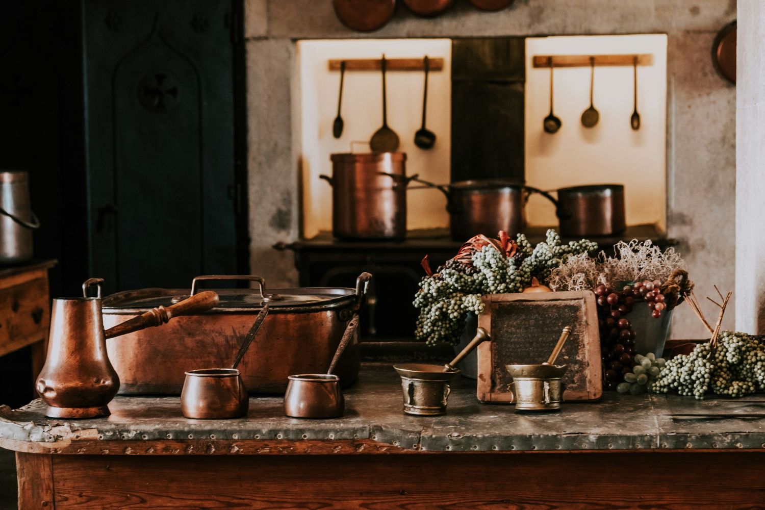 Country style rustic kitchen with copper pots and utensils on display on the wall.