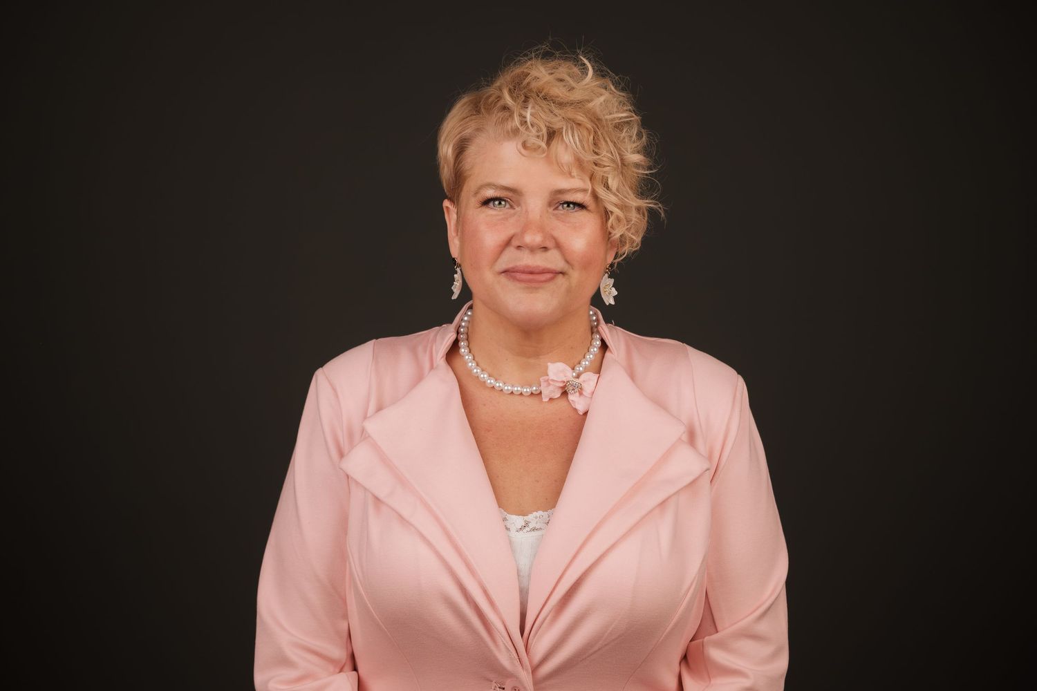 Professional headshot of a woman in a pink blazer smiling against a dark studio backdrop, taken at Echo Studio in Huntsville, Alabama.