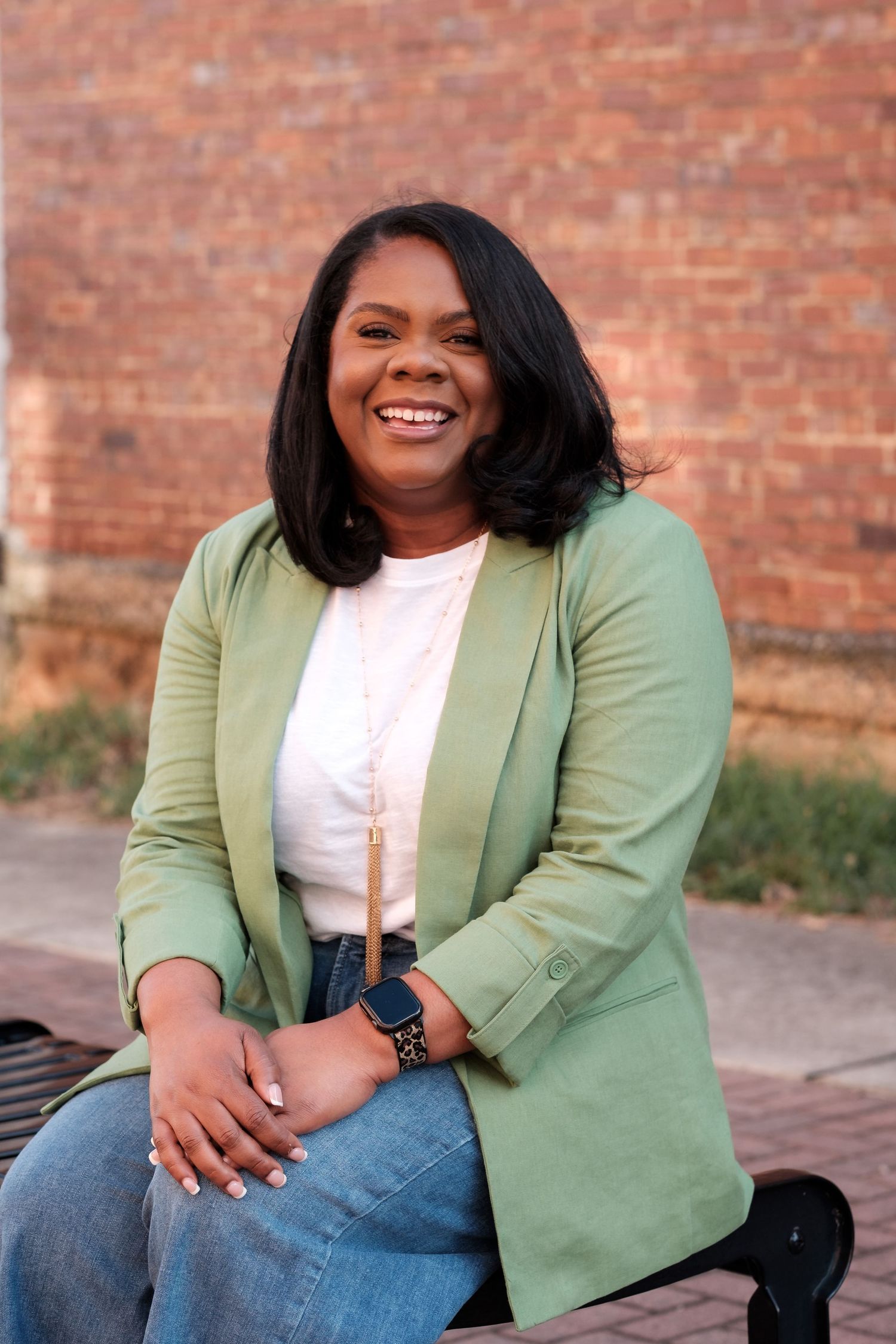 Professional outdoor headshot of a woman seated in natural light, photographed in Huntsville Alabama