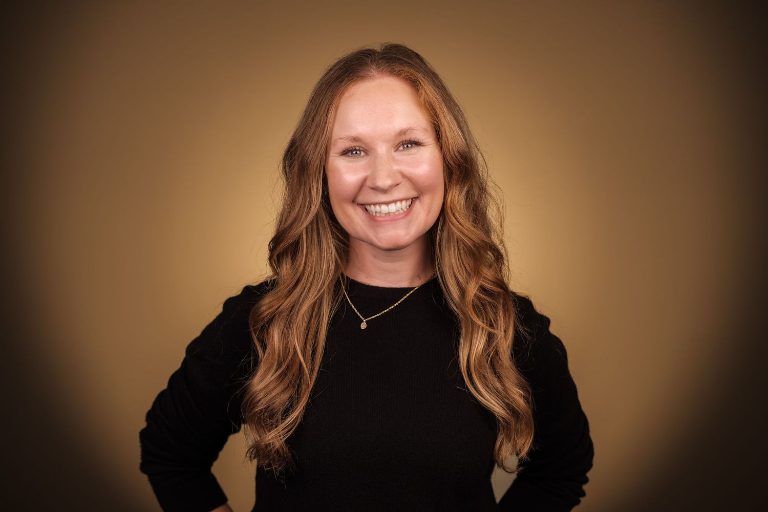 Professional headshot of a smiling woman with long red hair against a warm studio background, captured at Echo Studio in Huntsville, Alabama