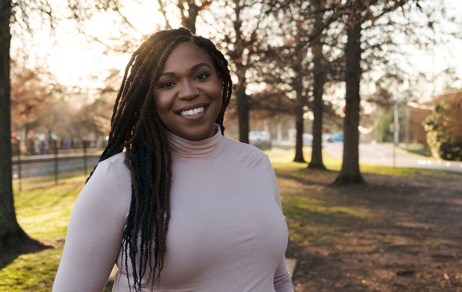 Professional outdoor headshot of a woman in natural light with trees in the background, photographed in Huntsville Alabama