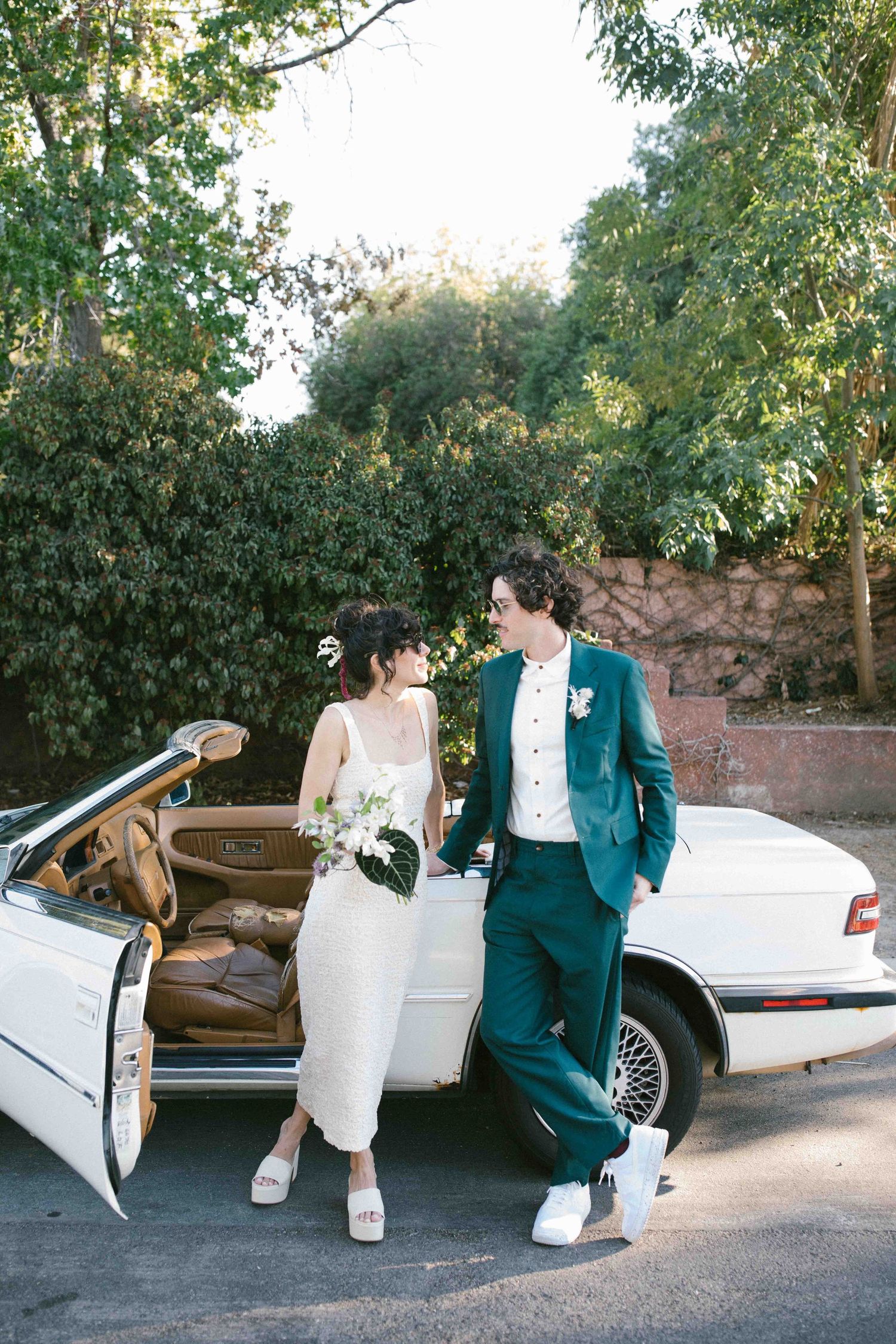 Candid documentary wedding moment of a couple standing next to their own vintage car
