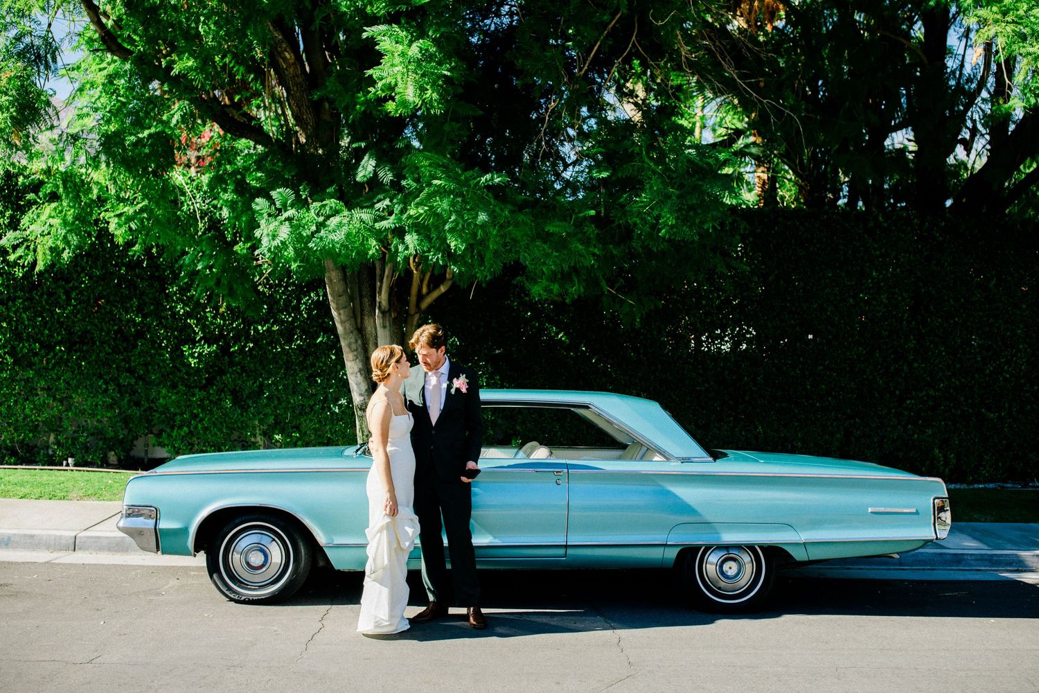 Bride and groom standing beside a vintage car on their wedding day