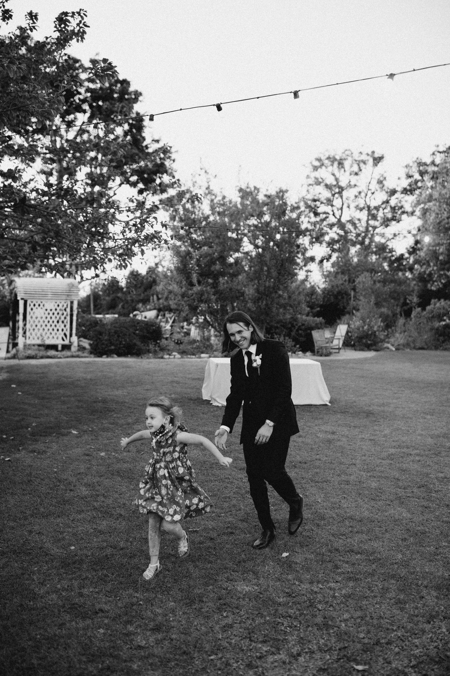Candid moment of a groom walking with a child during a wedding celebration