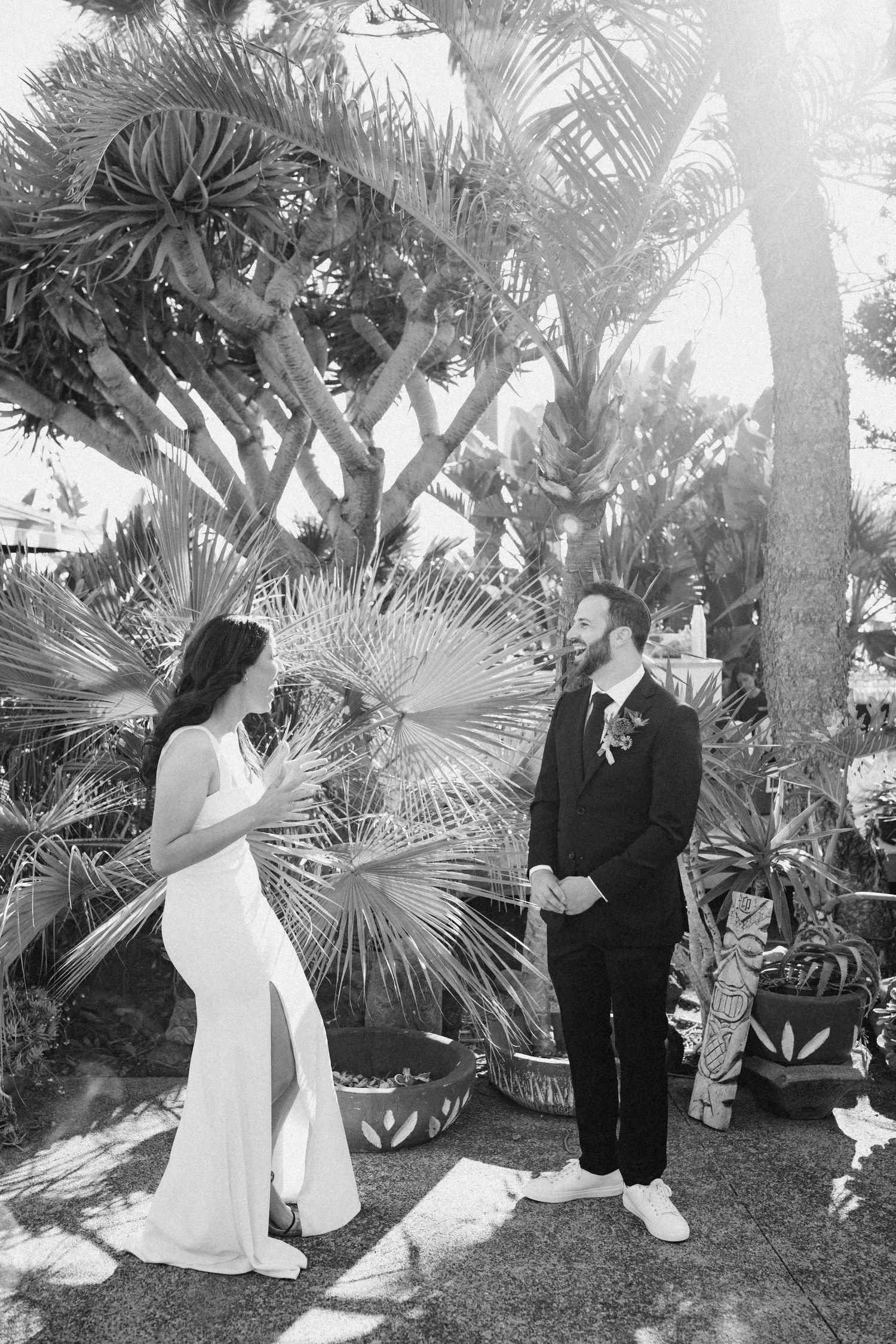 Bride and groom standing together beneath trees in a documentary moment