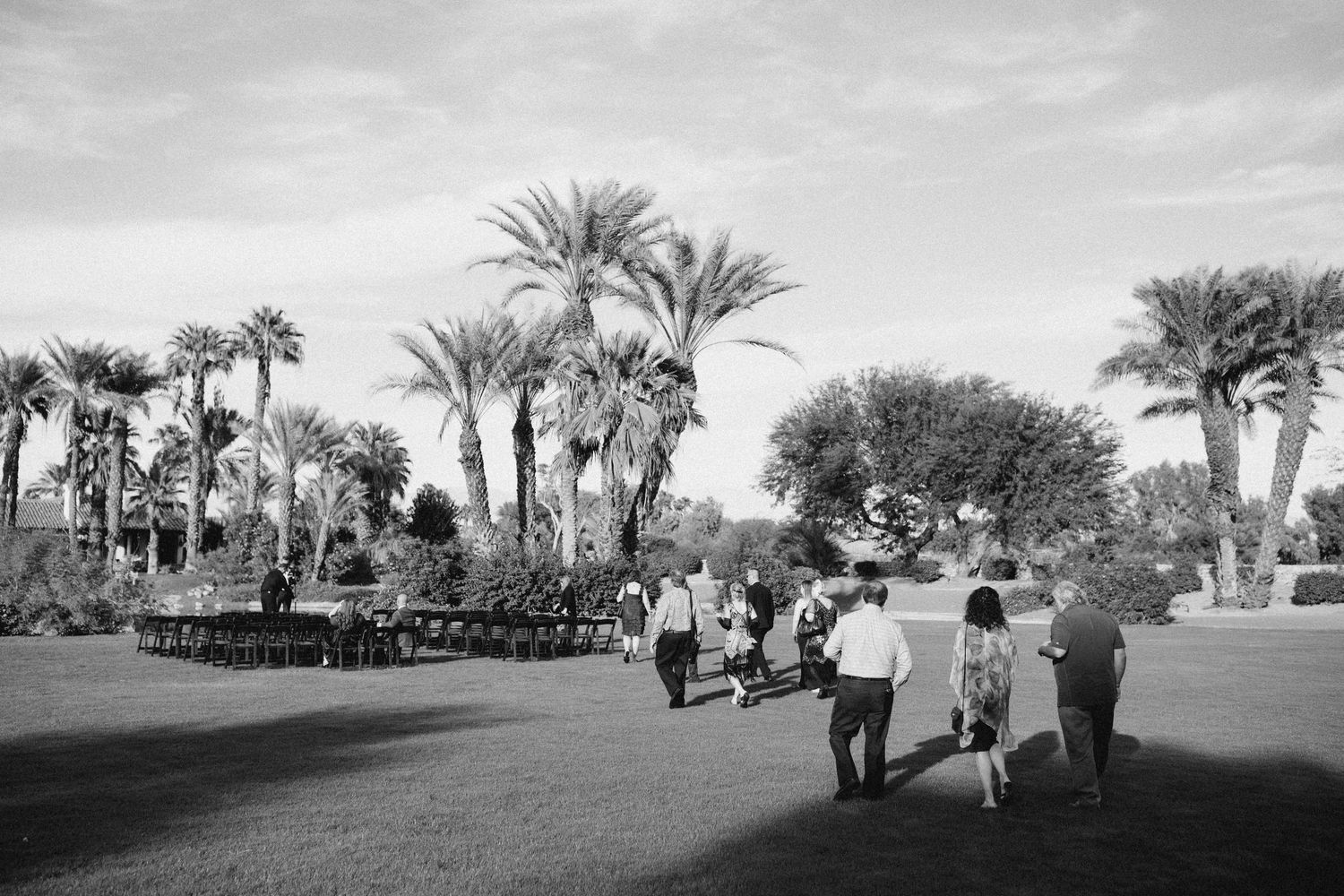 Wide documentary view of a wedding location with palm trees and guests arriving