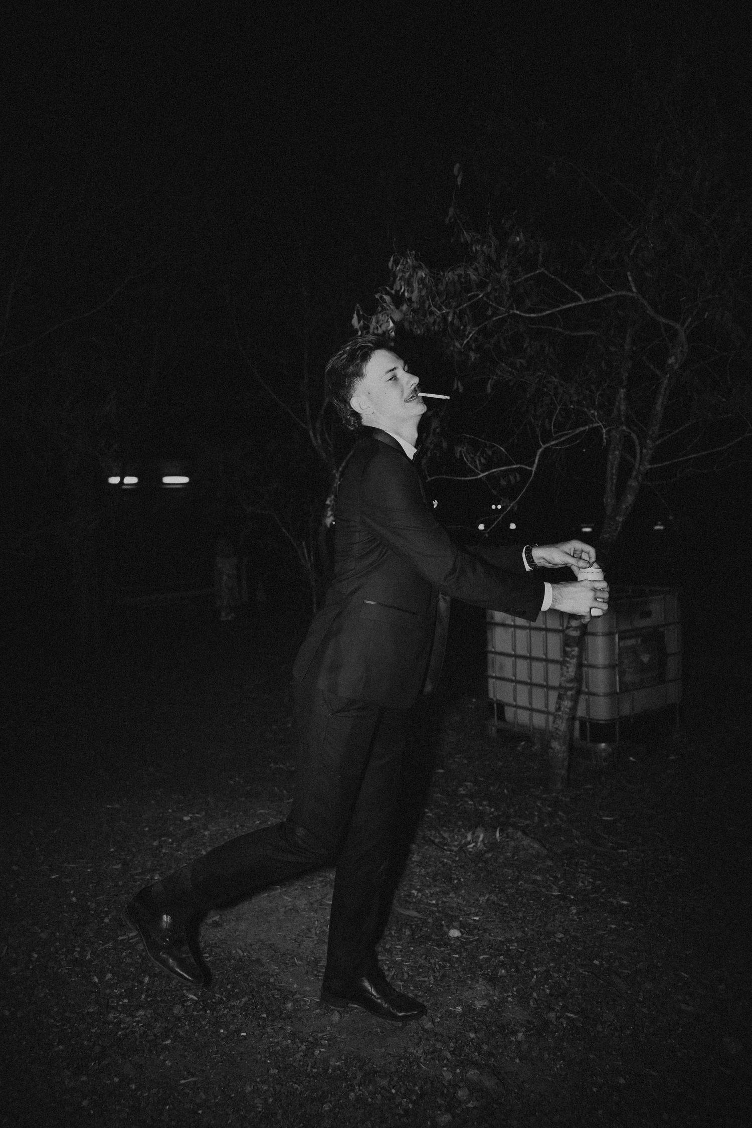 Black and white photo of person in formal attire posing dramatically at night.