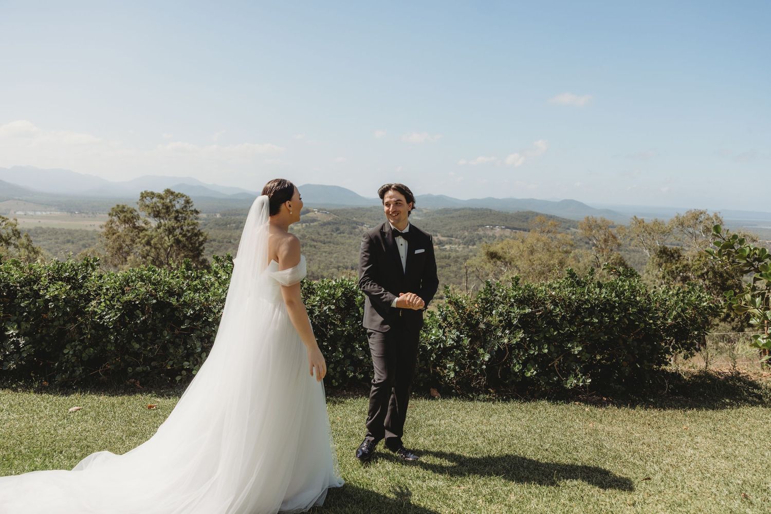 A romantic first look moment between newlyweds against a backdrop of rolling hills and mountains.