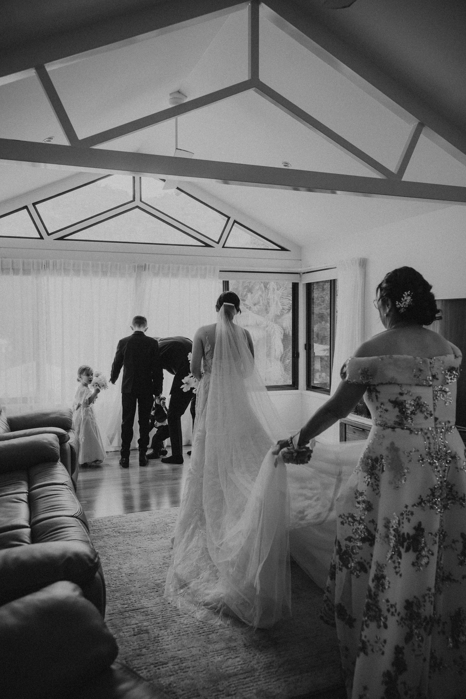 Black and white wedding sequence showing a couple walking through an elegant indoor venue with vaulted ceilings.
