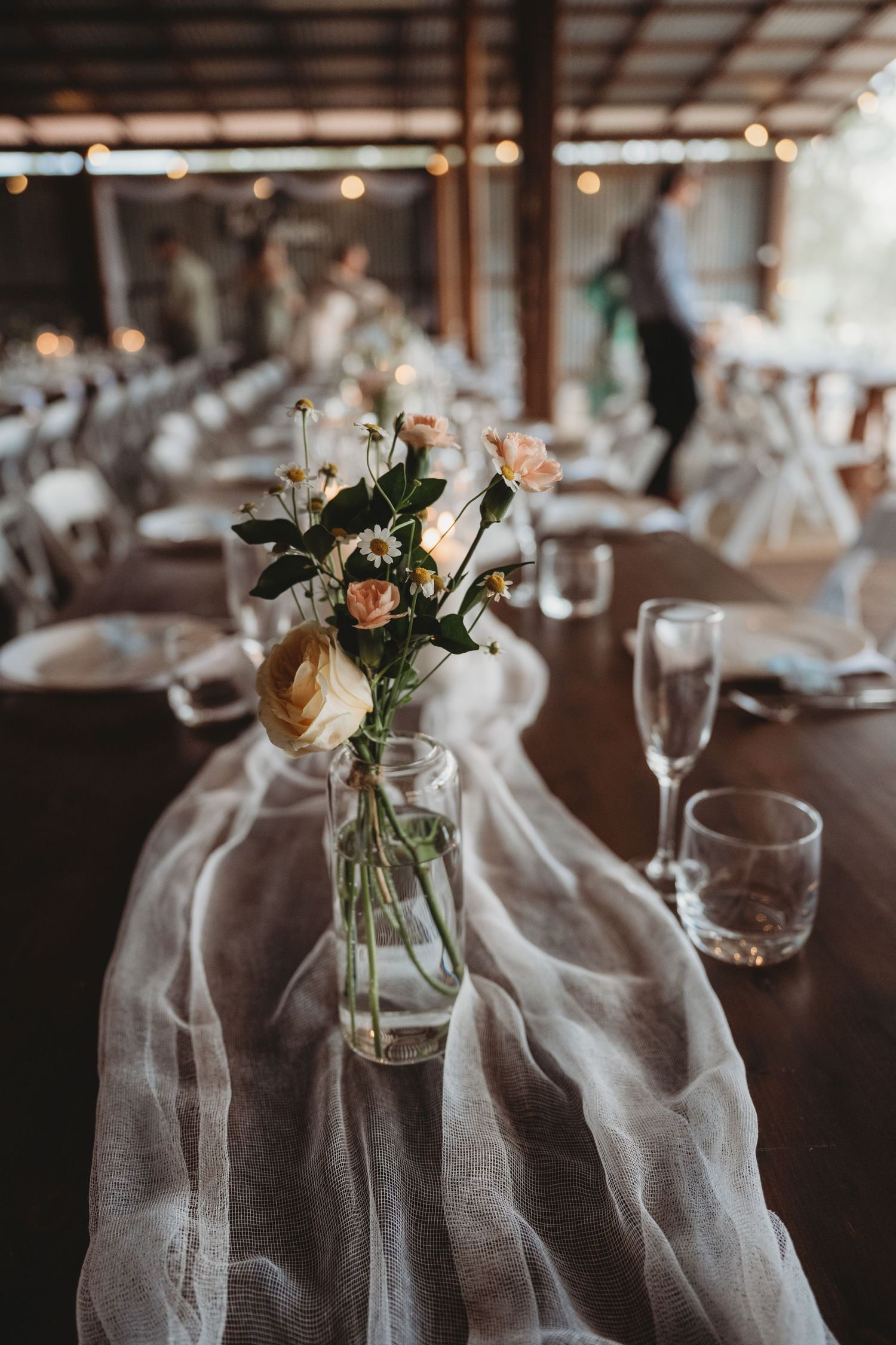Wedding reception table settings with soft gray linens and simple floral centerpieces.