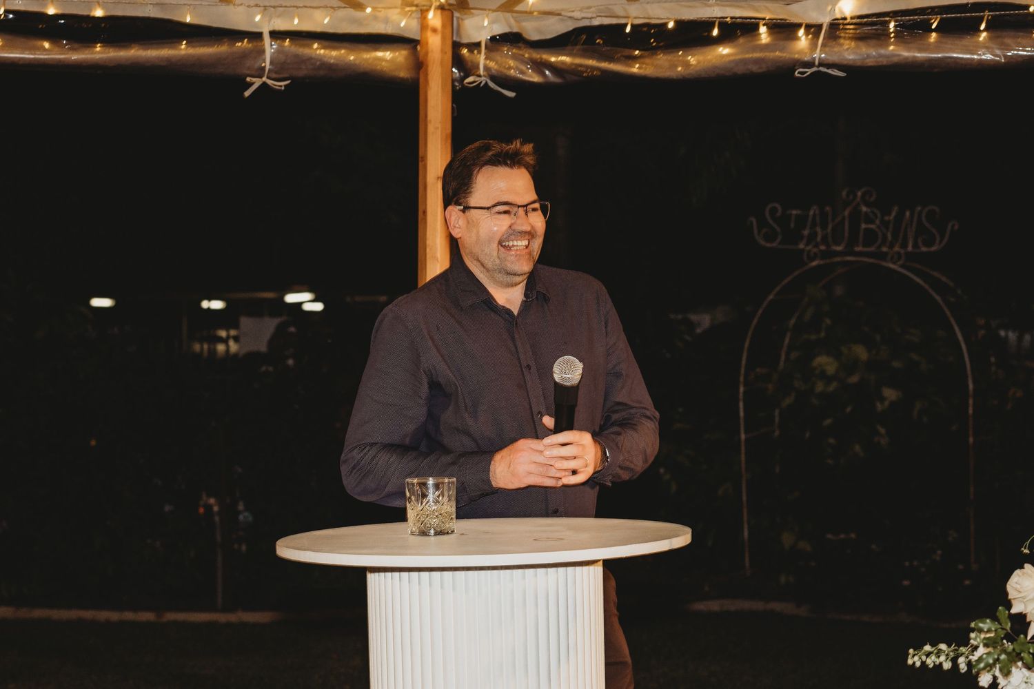 Evening wedding reception with modern white podiums and elegant lighting design.