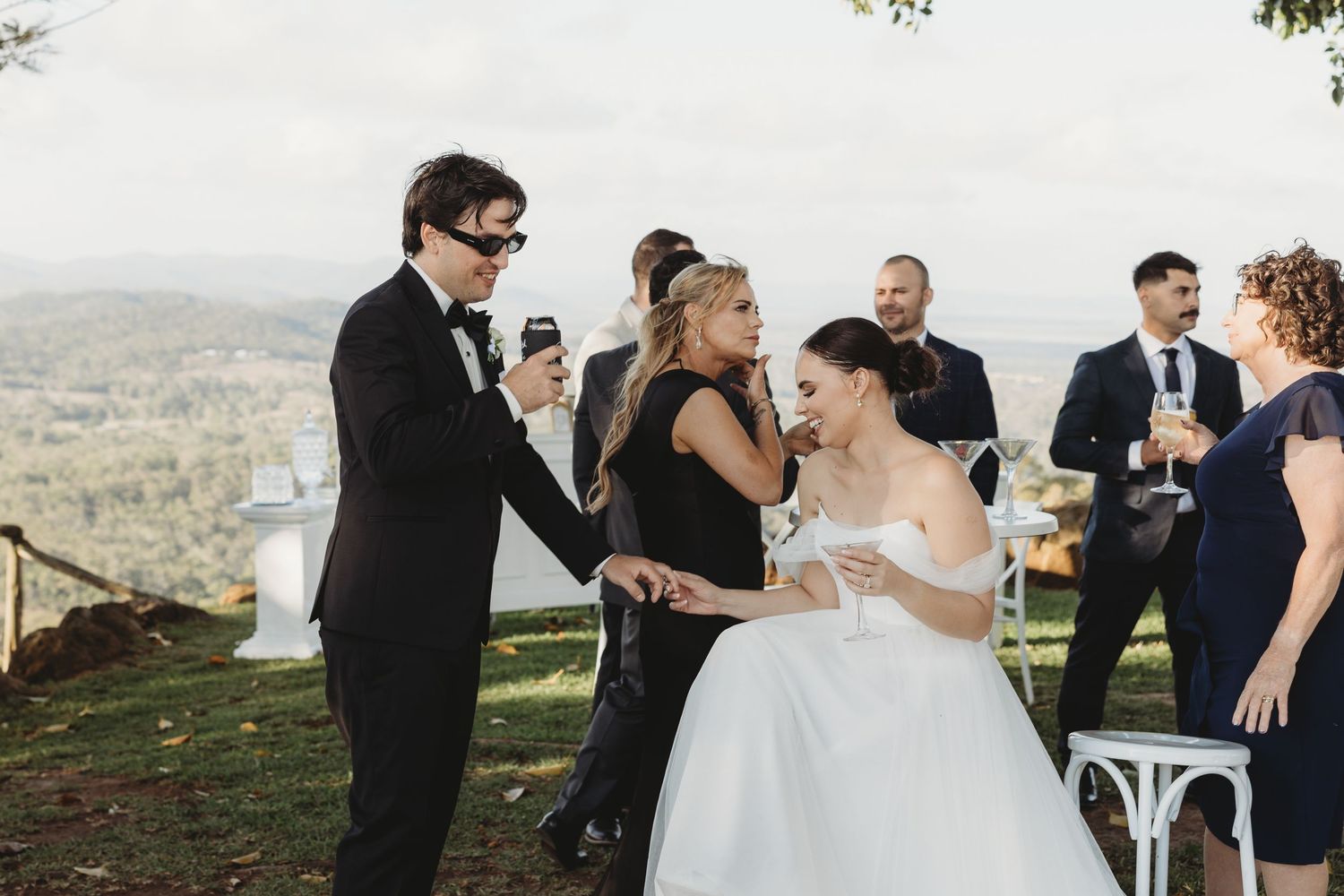 Wedding celebration with guests enjoying drinks on a scenic hilltop overlook.