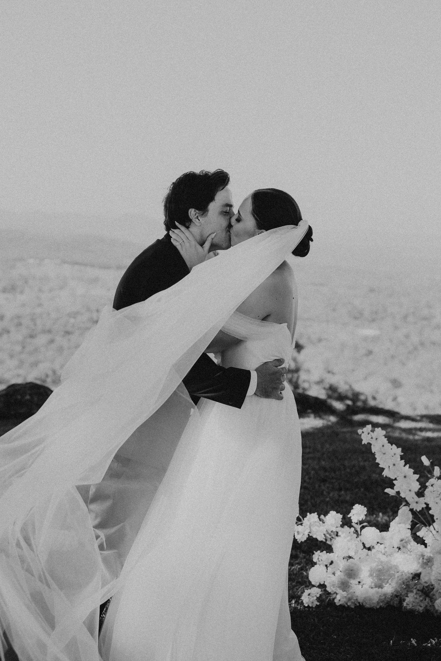 Artistic black and white wedding portraits showing intimate moments with a flowing veil.