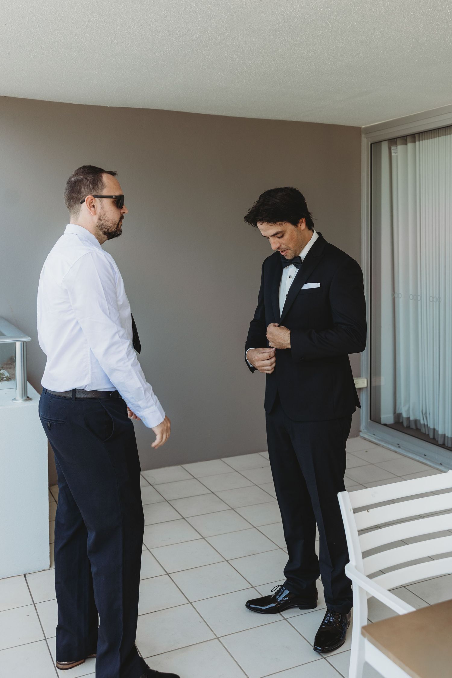 People in formal attire gather on a bright modern balcony.