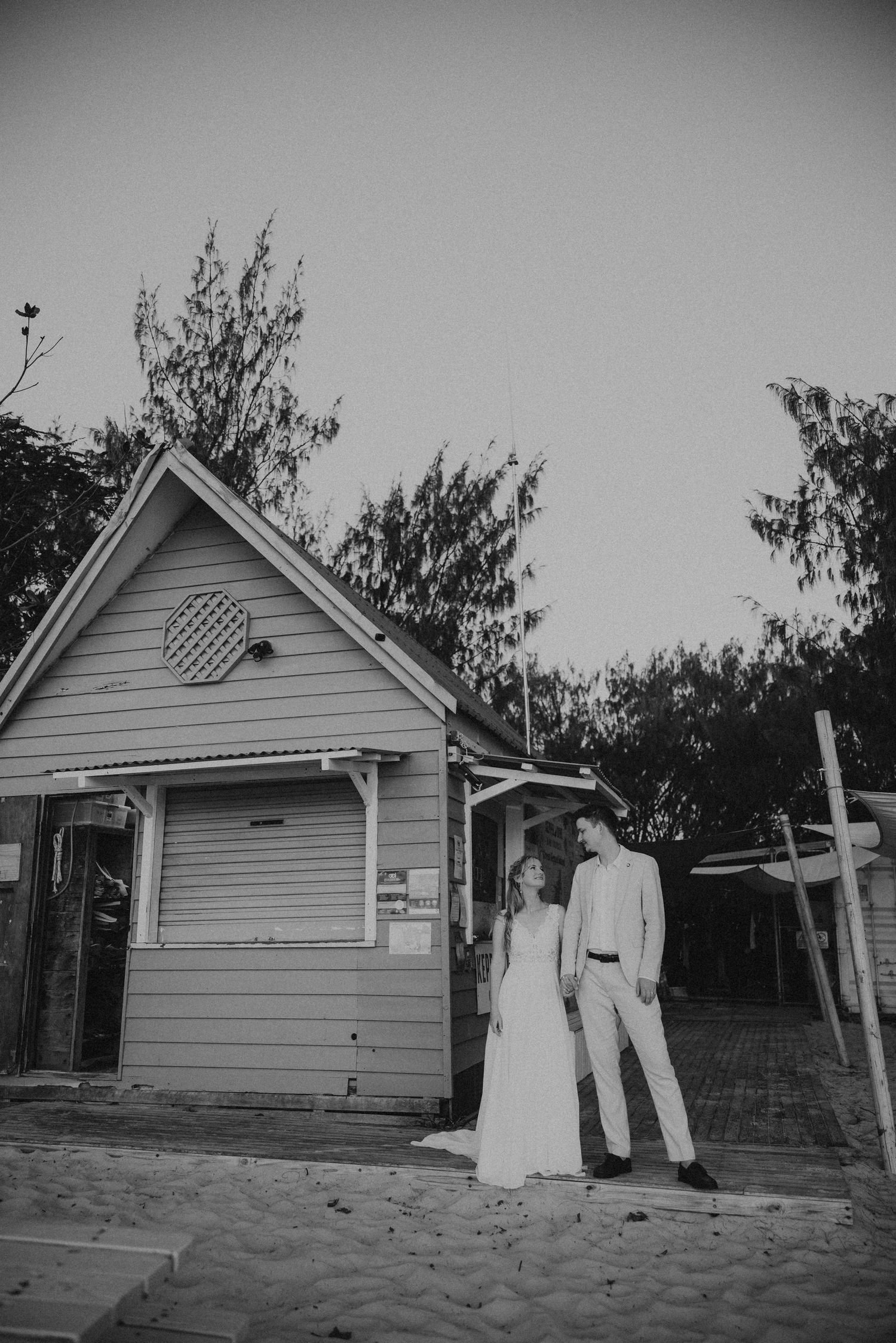 Black and white vintage photos show a couple posing outside a small wooden house.