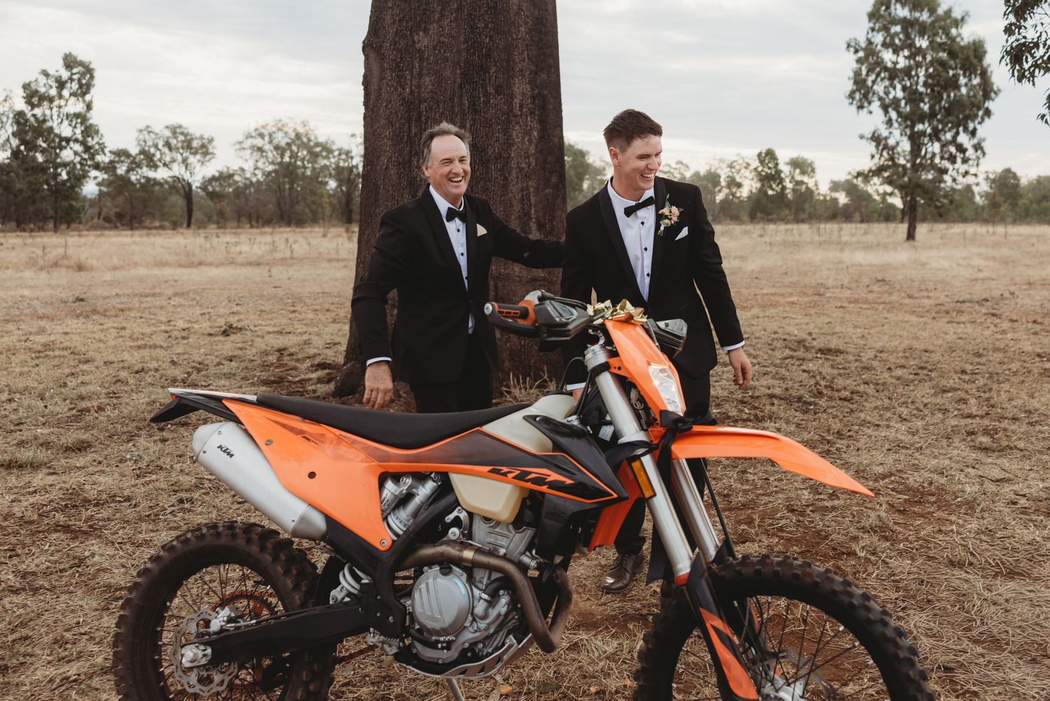 Orange dirt bike displayed prominently in rustic outdoor wedding setting.