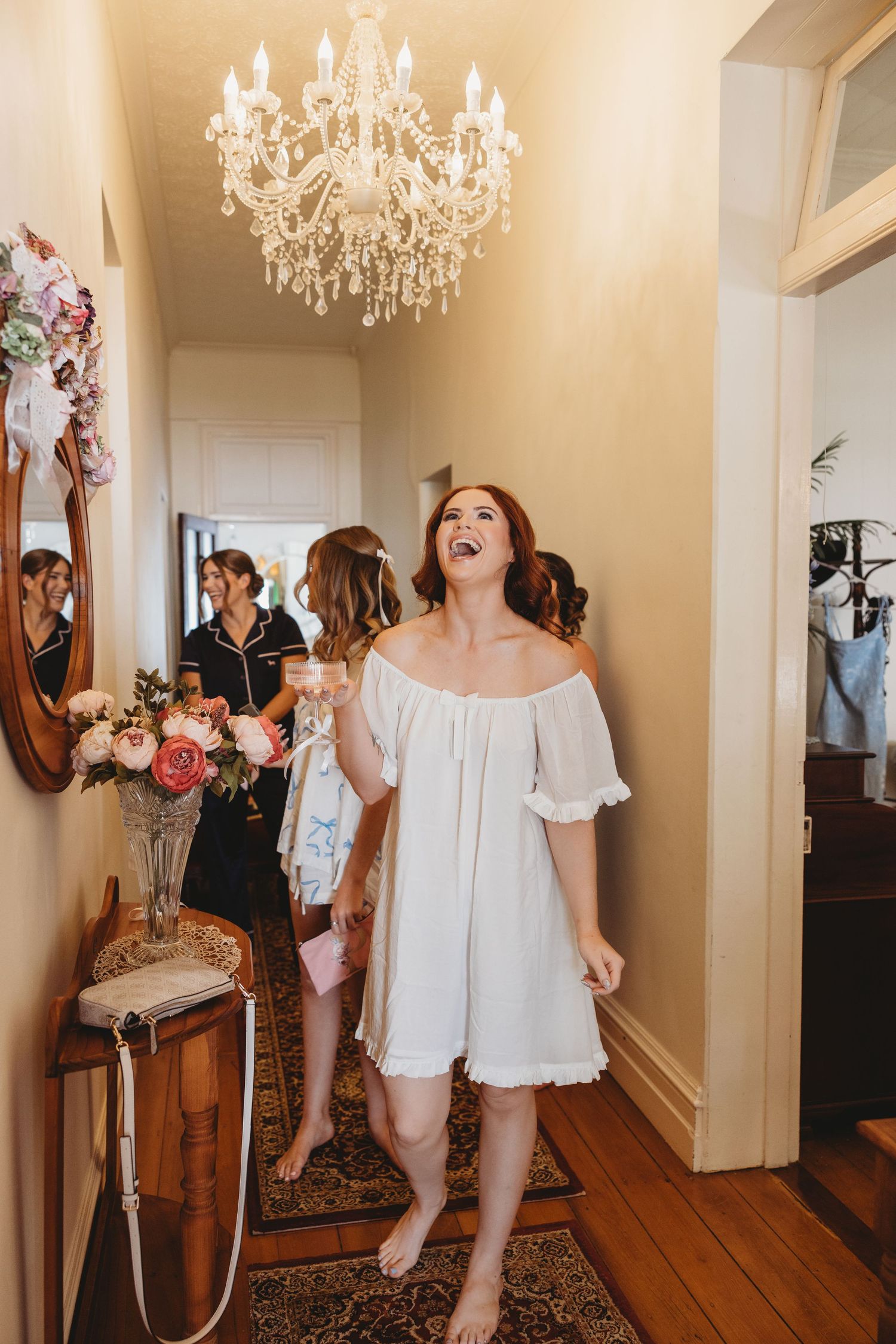 A series of joyful moments captured in an elegant hallway with crystal chandeliers and hardwood floors Rockhampton Wedding
