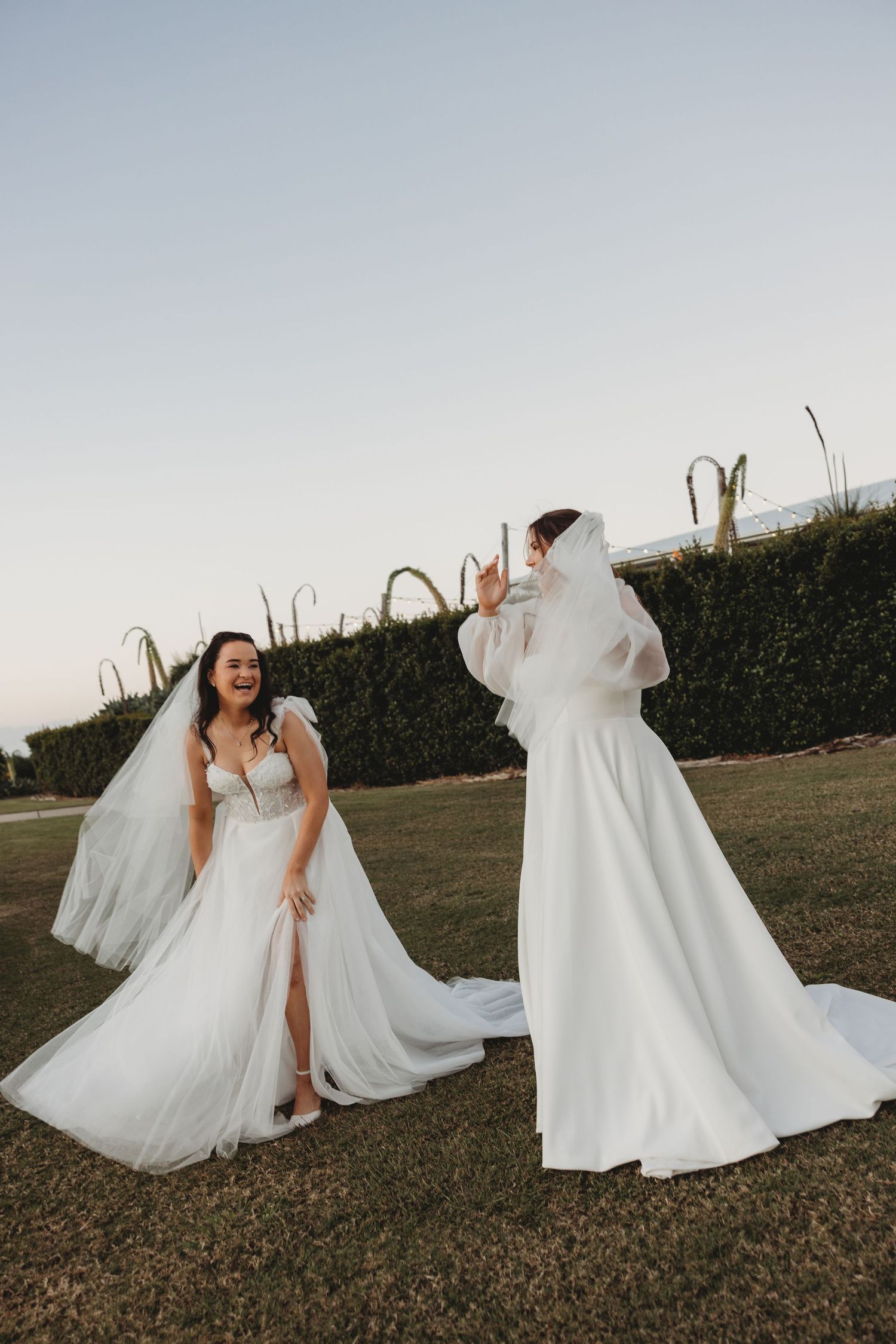 Joyful movement captured as white dresses twirl in an outdoor field setting.