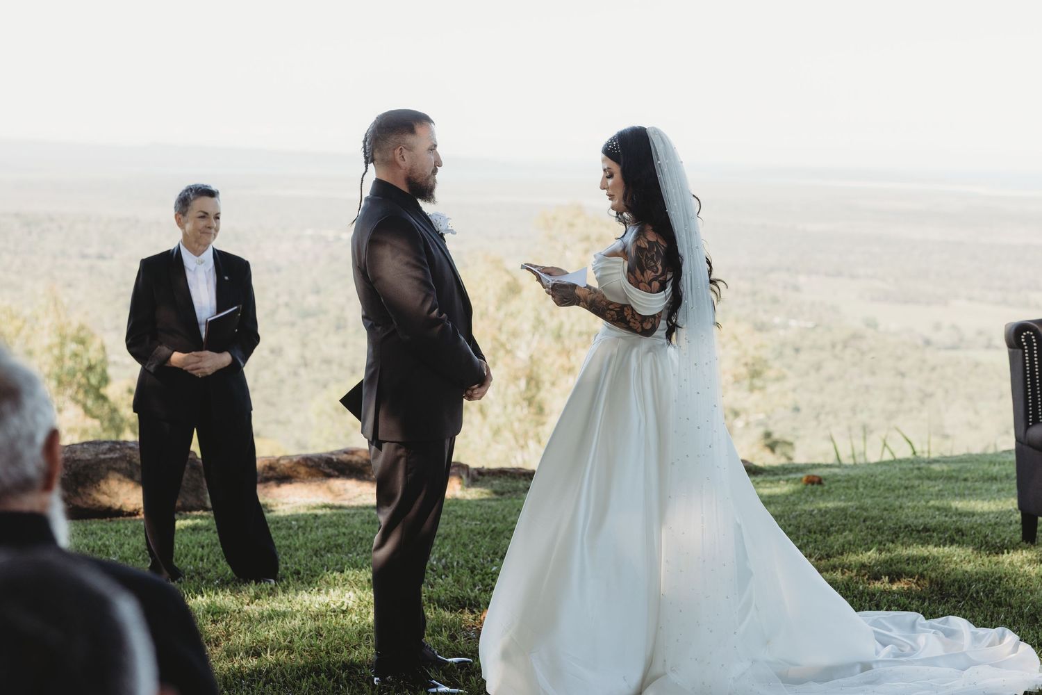 Couple exchanging vows during an outdoor wedding ceremony with mountain views in the background.