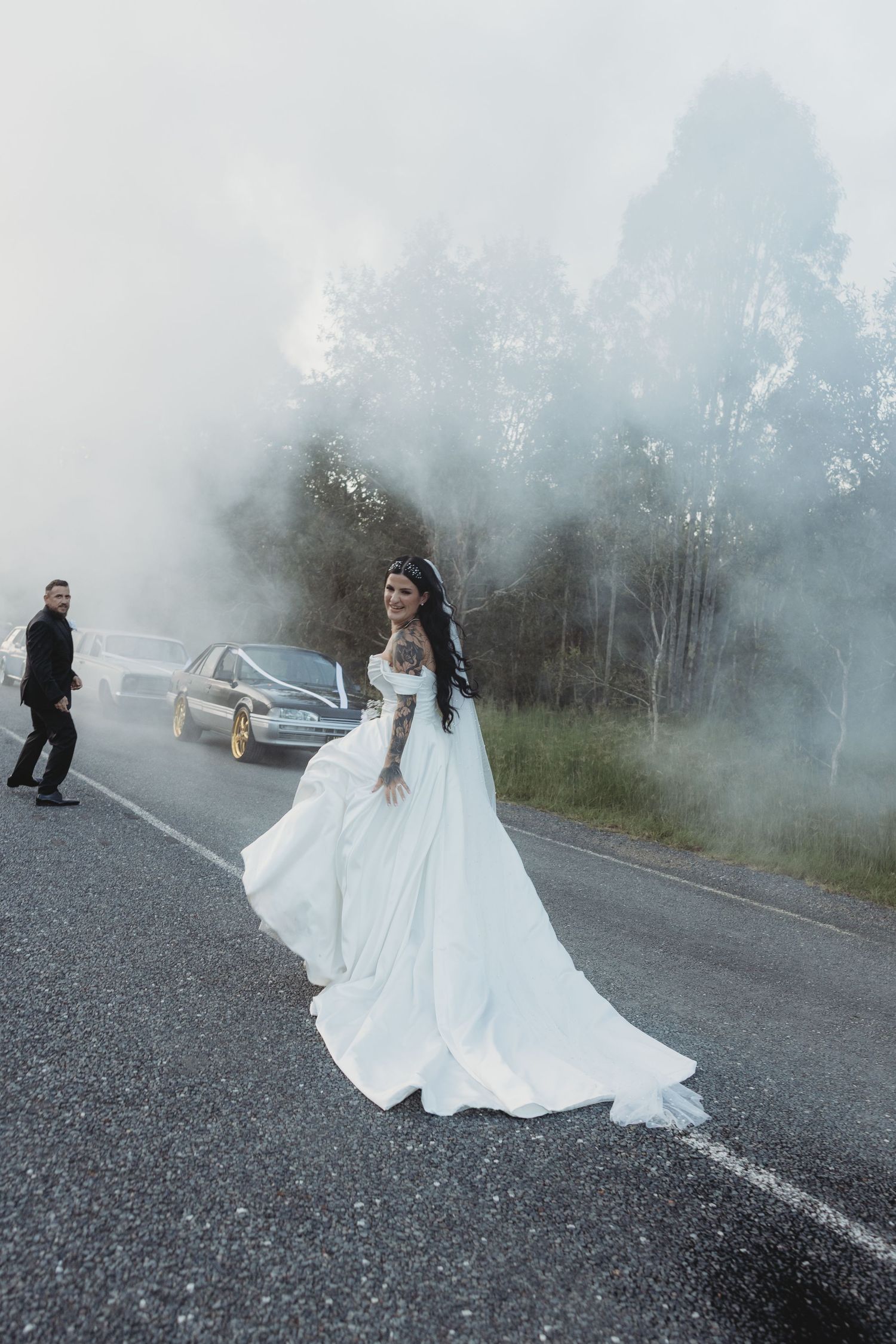 Dramatic foggy wedding photoshoot on a misty road with flowing white dress.