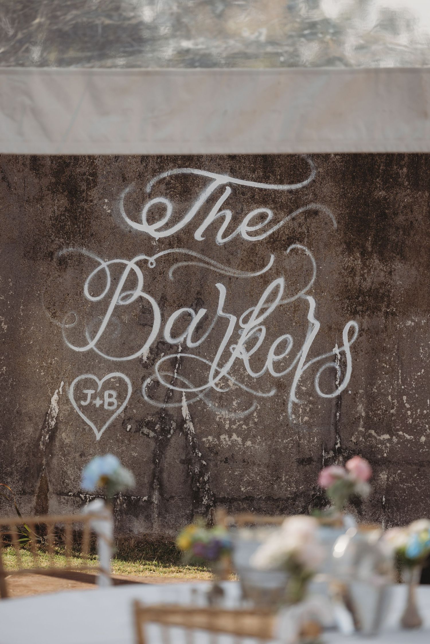 Elegant wedding sign reading The Barkers with J+B initials in a heart, displayed at a beautifully decorated reception venue.
