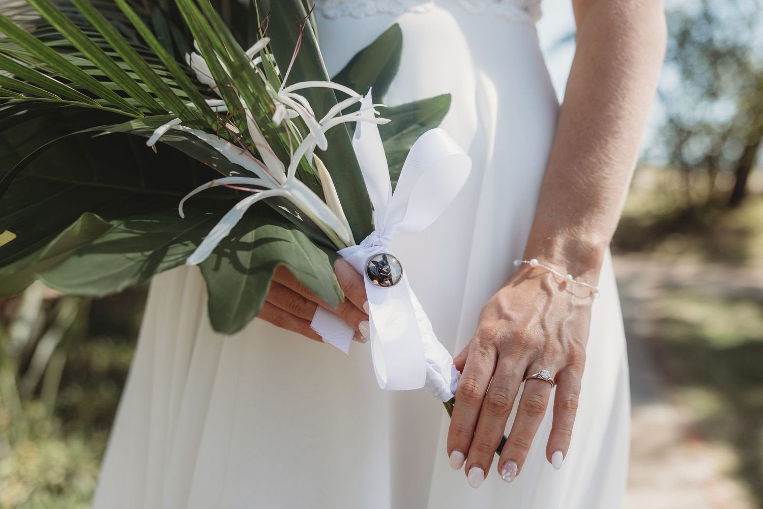 Wedding bouquet and dress details captured in natural outdoor lighting.