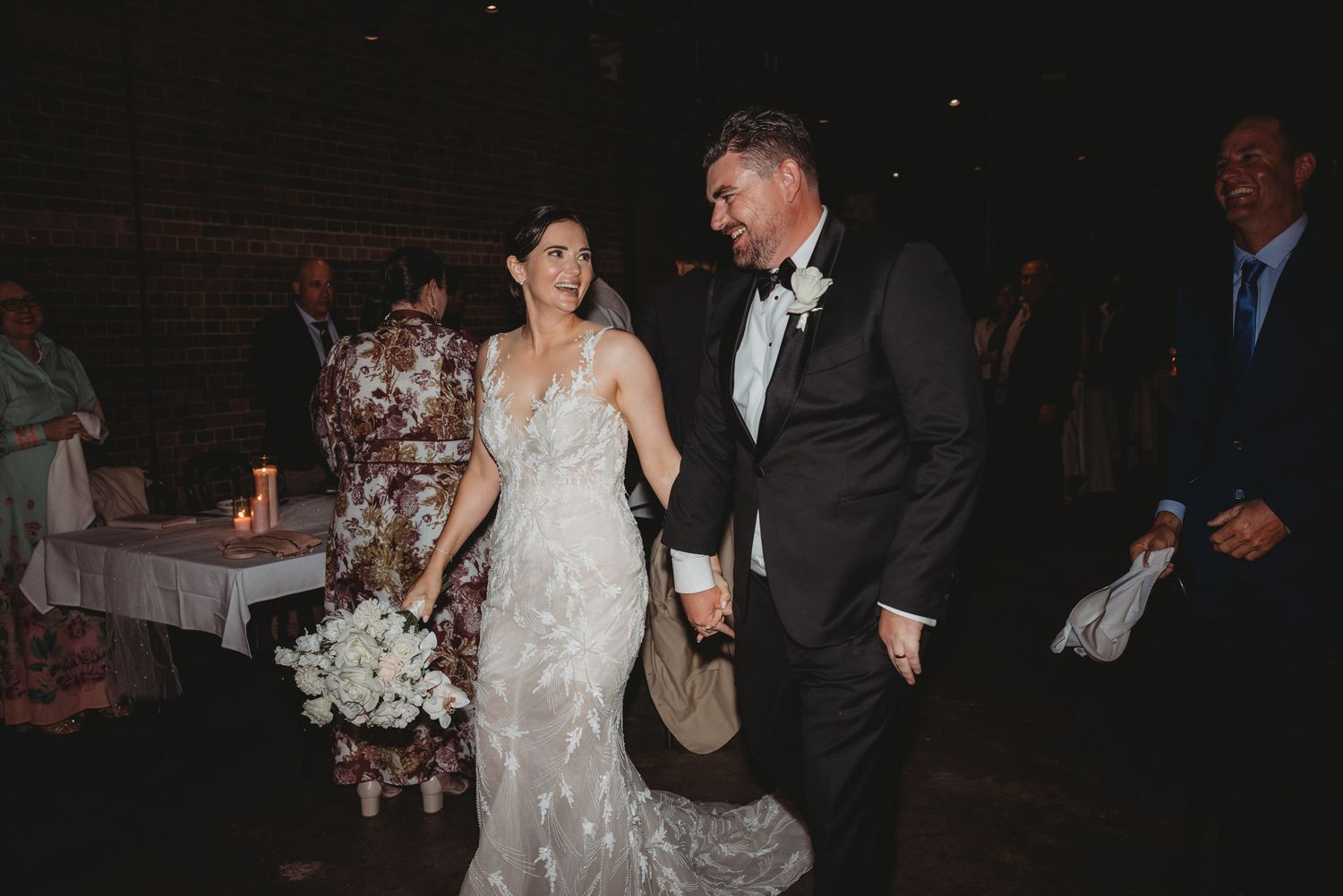 Couple walking through their reception venue in formal wedding attire.