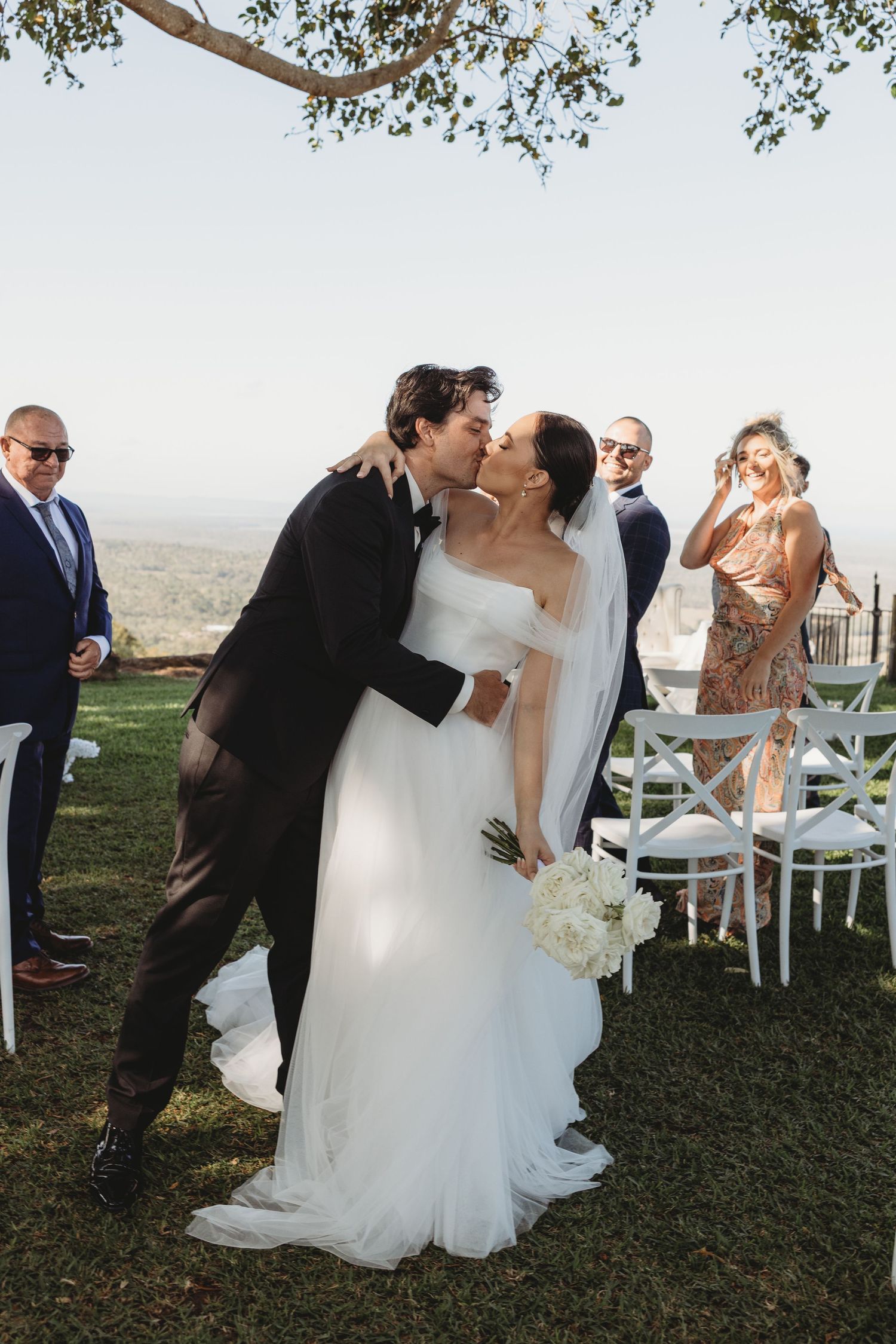 Outdoor wedding ceremony with white chairs and scenic mountain views in the background.