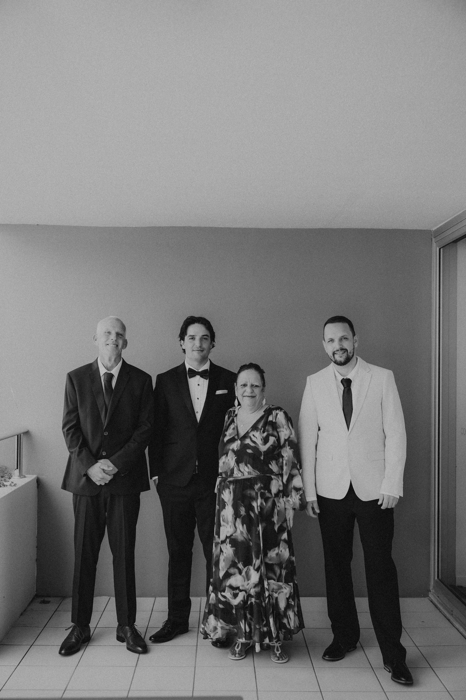 A black and white group photo of formally dressed people lined up against a wall.