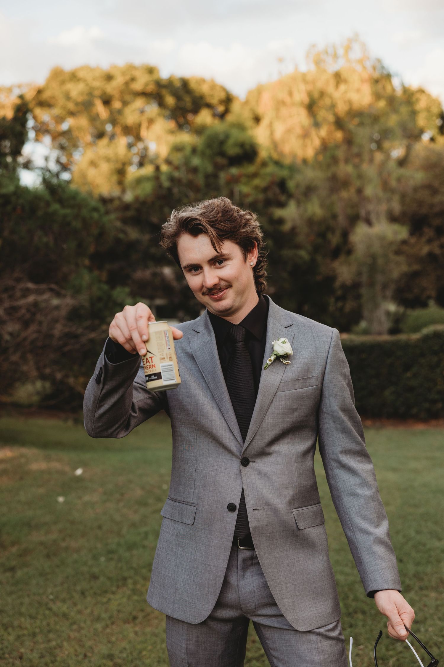A person in a grey suit poses playfully for wedding photos outdoors Central Queensland Wedding