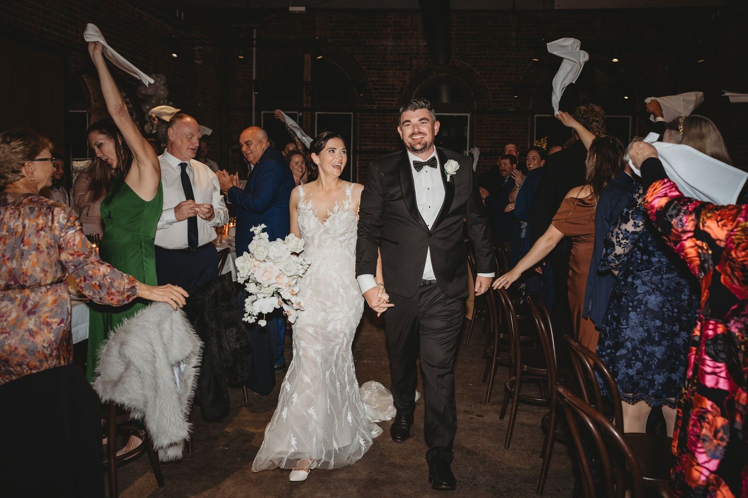 Wedding reception dance floor filled with guests celebrating in a rustic indoor venue.
