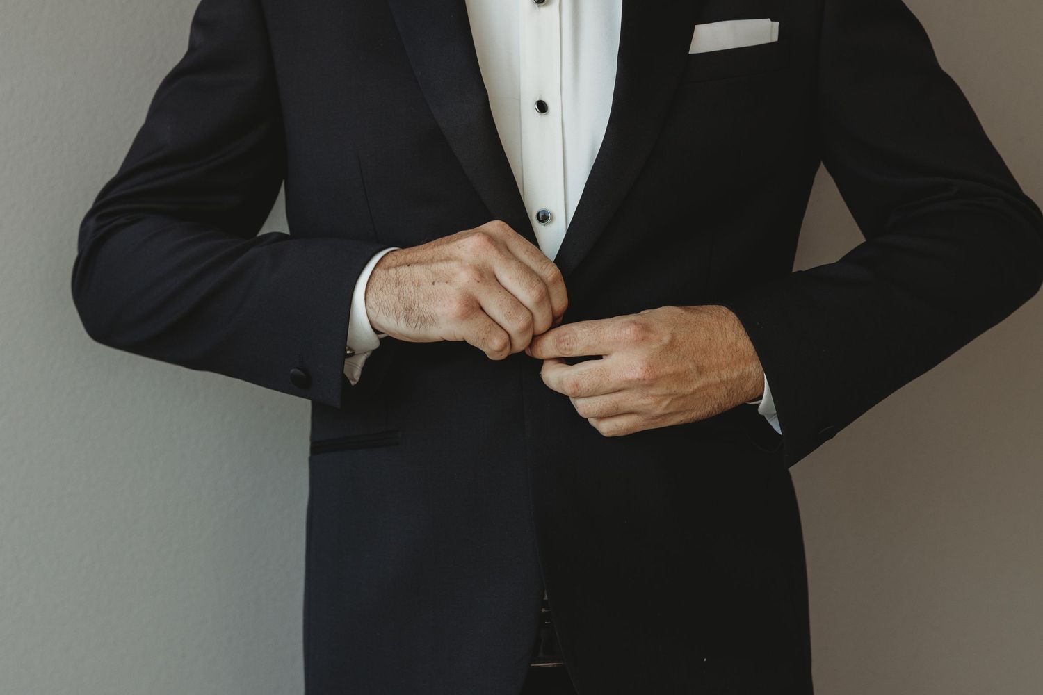 Someone in formal attire makes final adjustments to their tuxedo and bowtie.