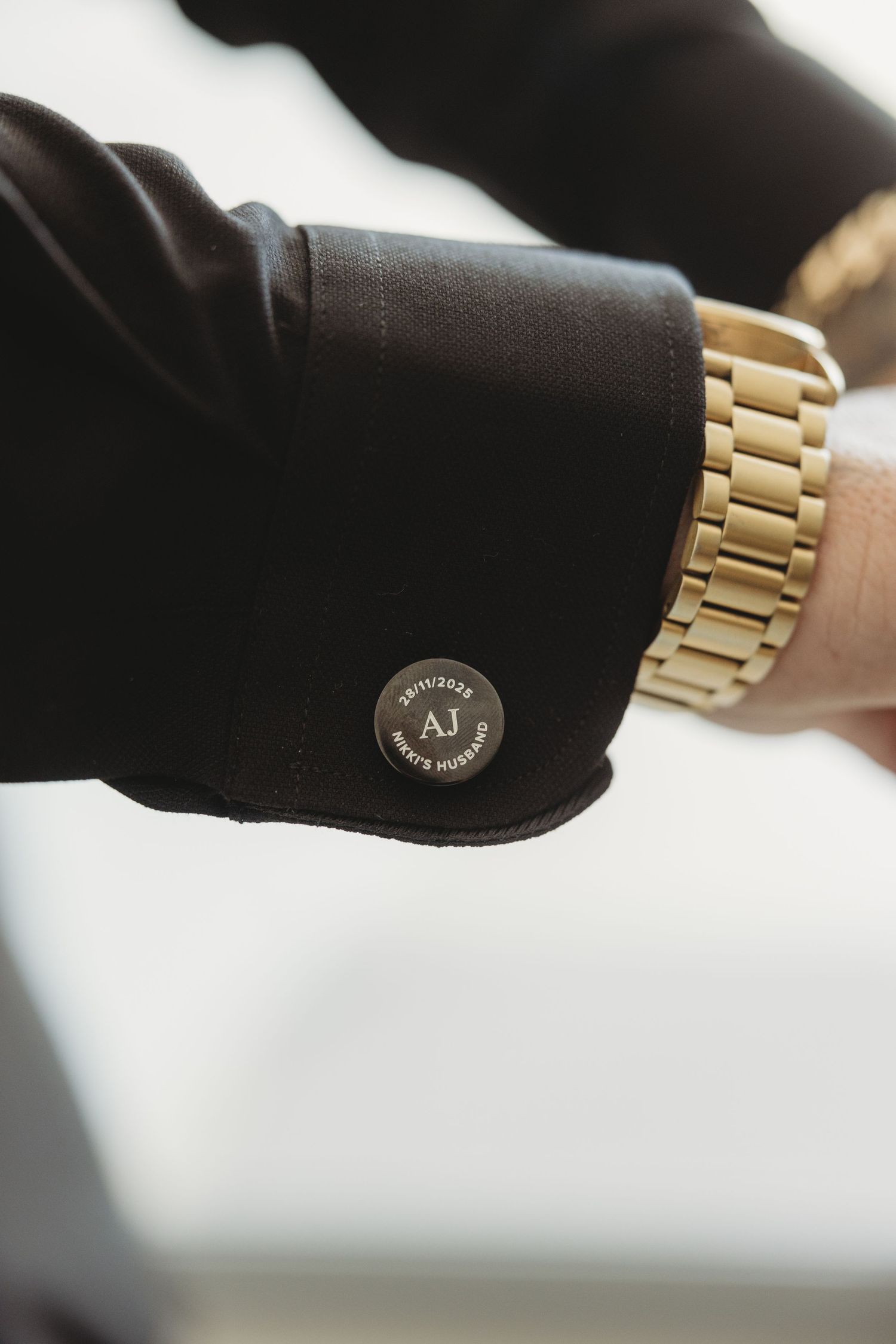 Close-up details of a gold watch being adjusted on a black surface.