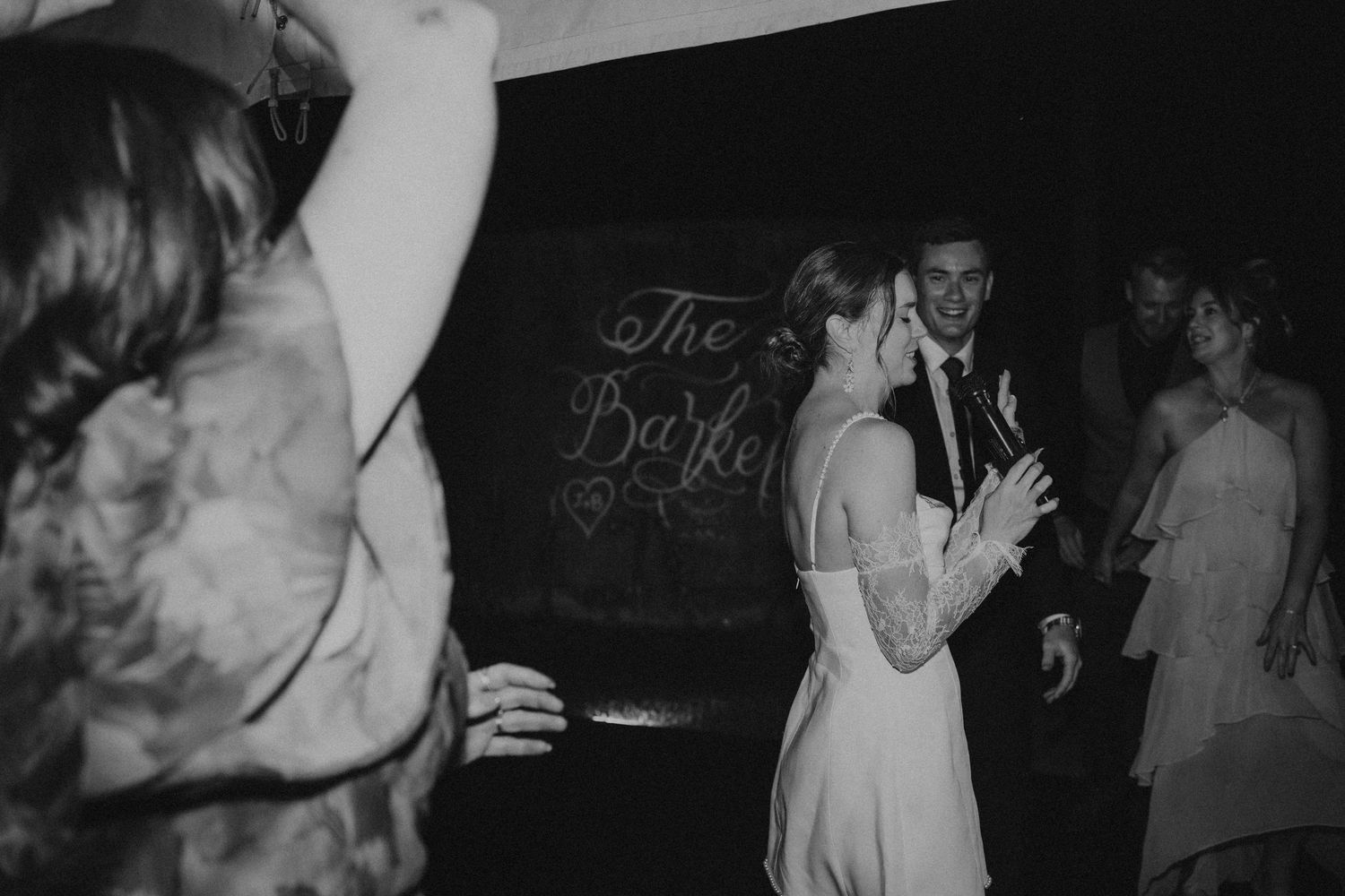Bride and groom share joyful dance moment in black and white wedding reception photo.