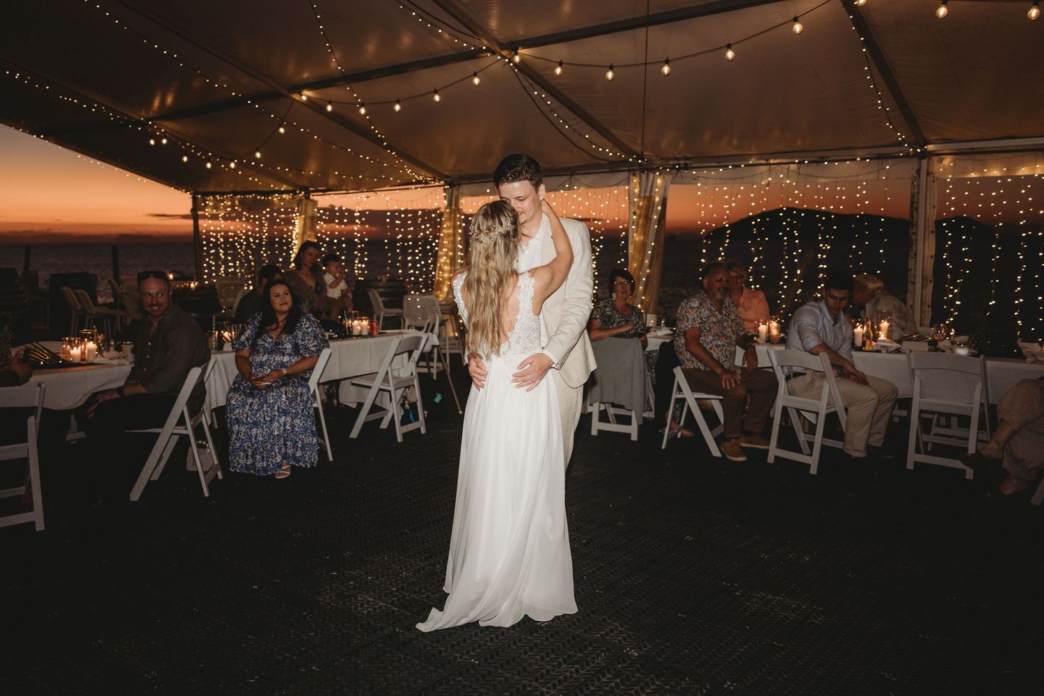 A wedding celebration in a tent venue with twinkle lights and white decor.