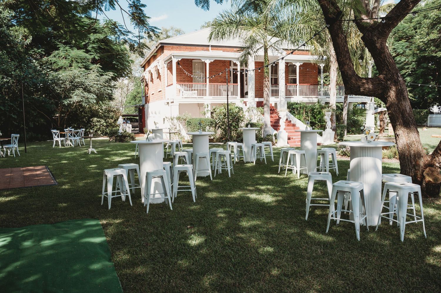 Outdoor wedding reception setup with white metal chairs arranged under shady trees at St Aubins Rockhampton