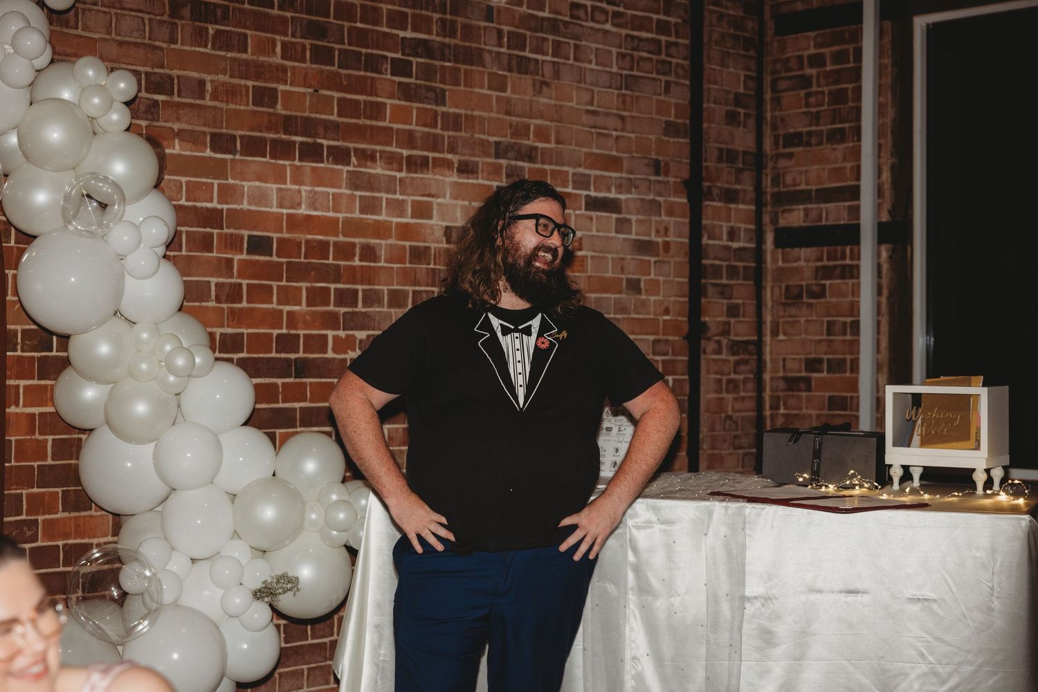 Wedding reception venue with exposed brick walls decorated with white balloon arches.